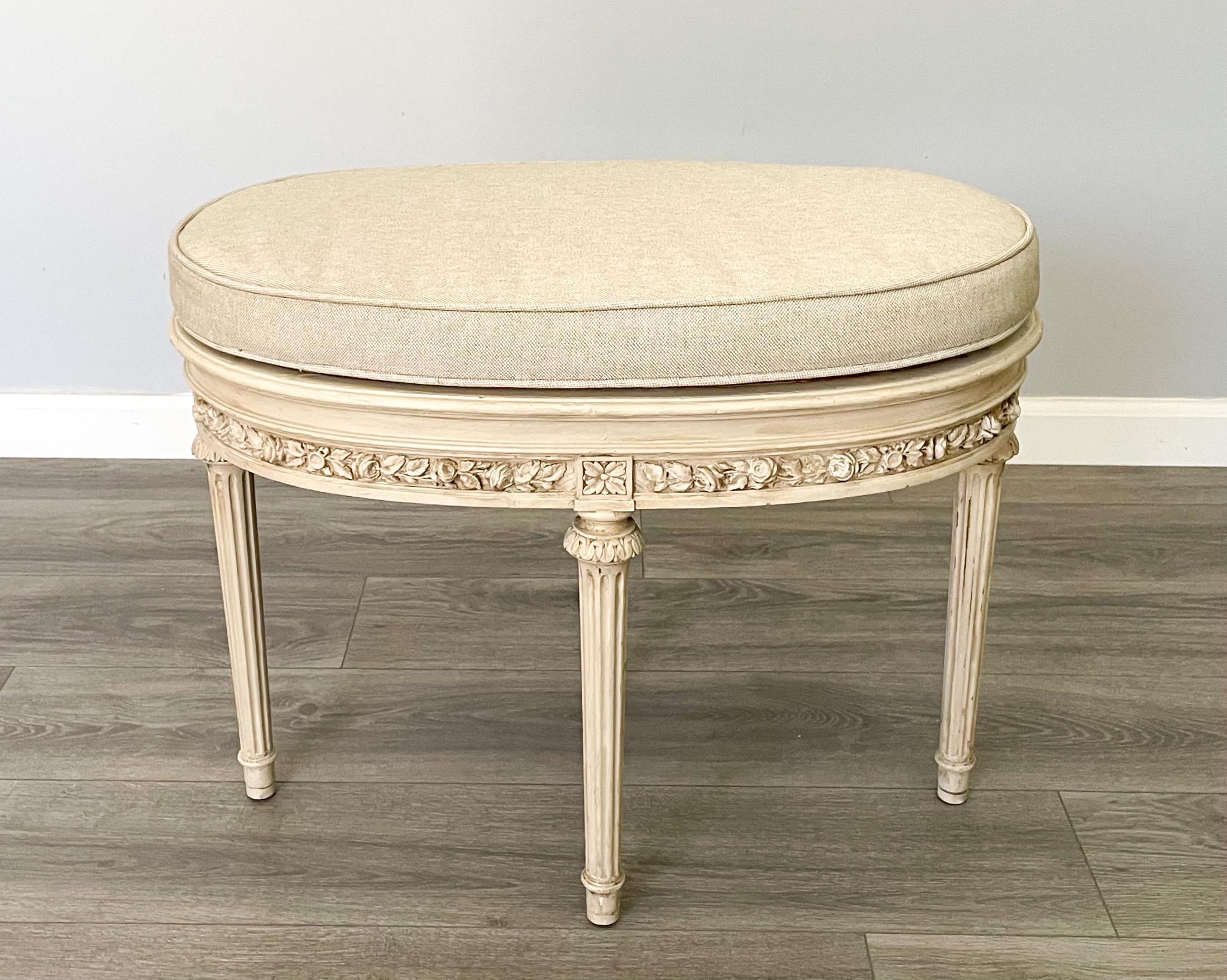 Beautiful, French 1940s painted bench in the Louis XVI style.

The bench features an oval shaped frame with delicately carved decorations and a distressed paint finish. 

The newly upholstered cushion is covered in Belgian linen and is