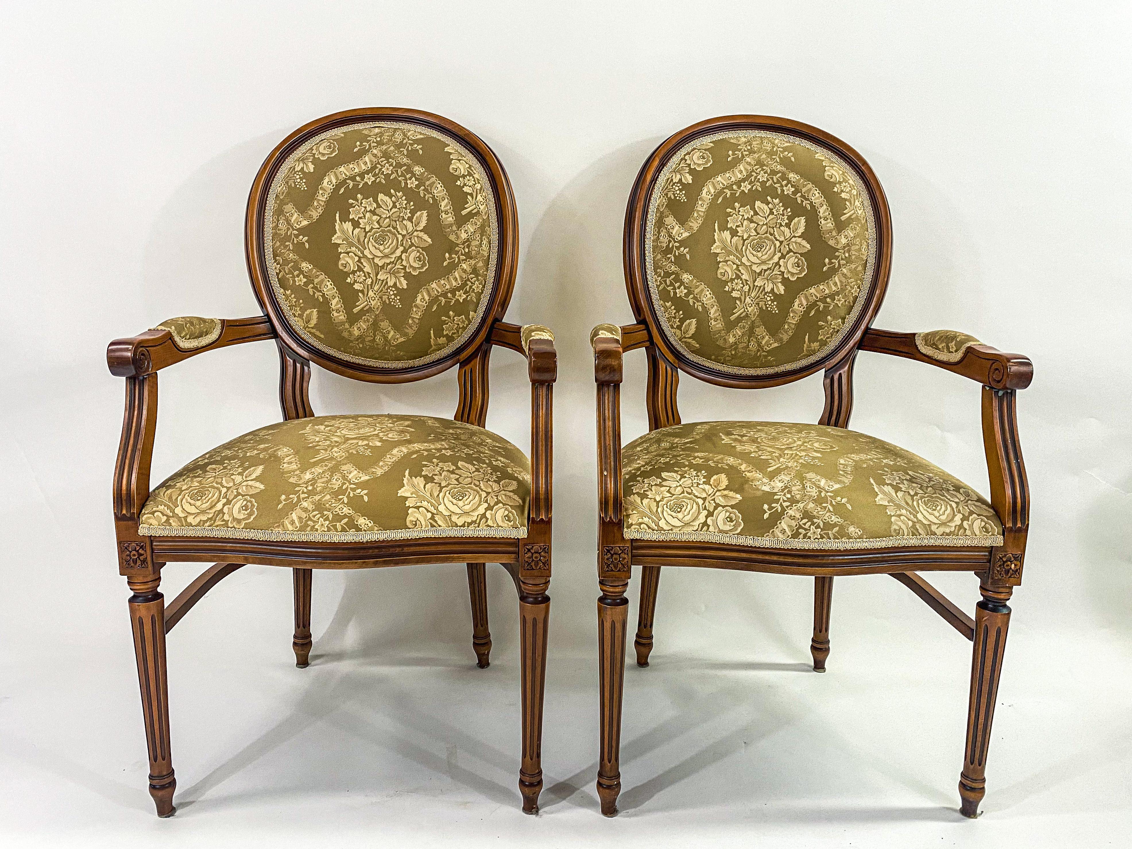 An elegant pair of French Louis XVI bergere or arm chairs. The chairs feature quality upholstery in light green with a hint of gold and is embellished with beautiful floral. details. The frame of the chair is finely carved of maple wood . The