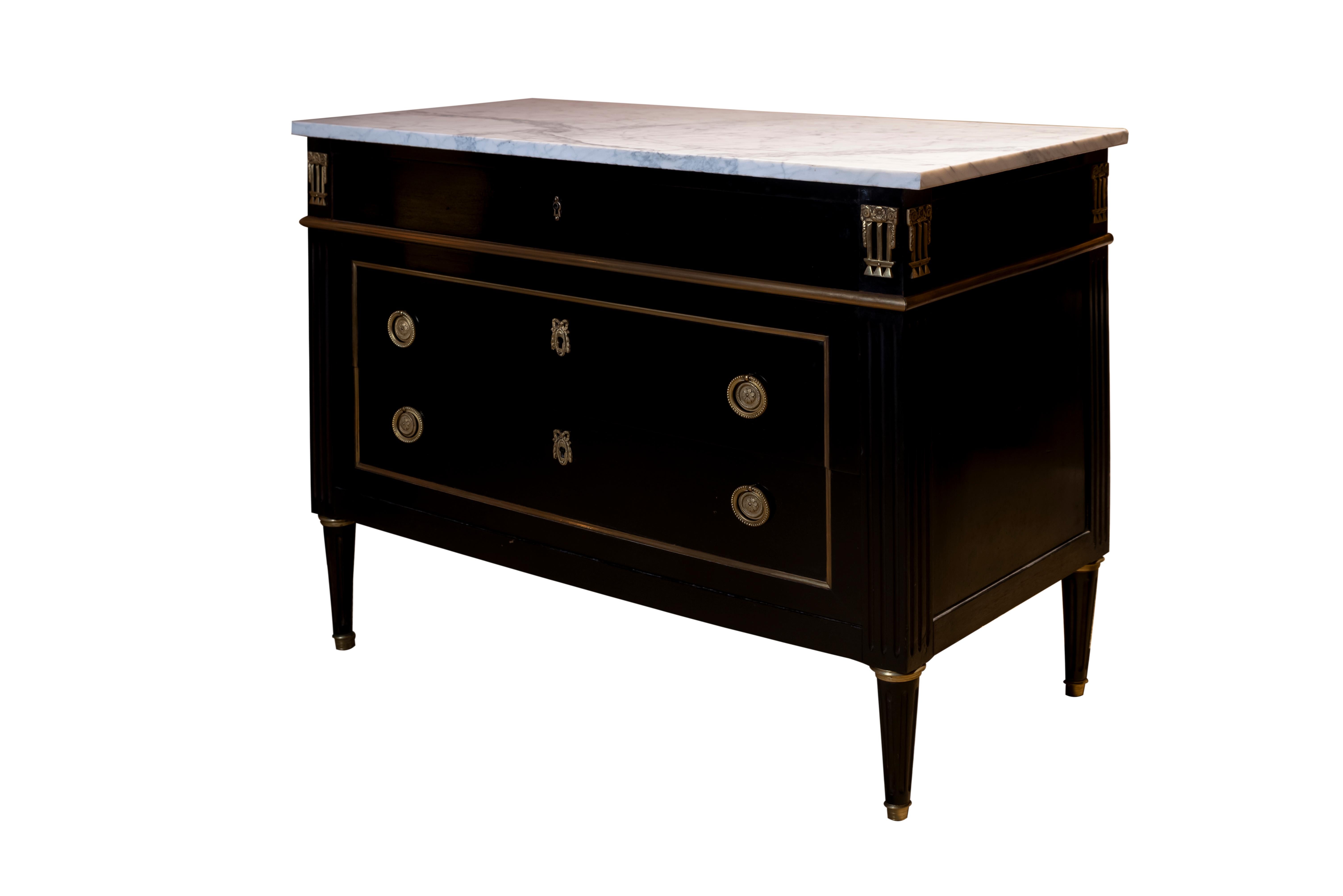 20th century French Louis XVI style black lacquered chest of drawers or commode. Topped with a white marble in four fluted legs with brass details. Three drawers with brass decoration and details.