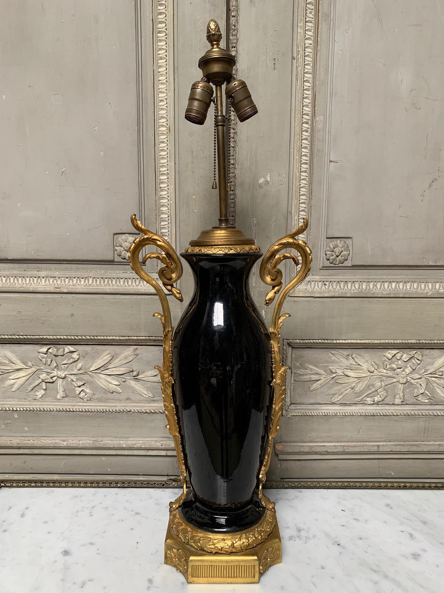 A 19th century French gilt bronze mounted black porcelain lamp base in the Louis XVI style. The bronze fittings are very fine quality and scale. This is a beautiful lamp that would work in a variety of interiors. The height is to the top of the lamp