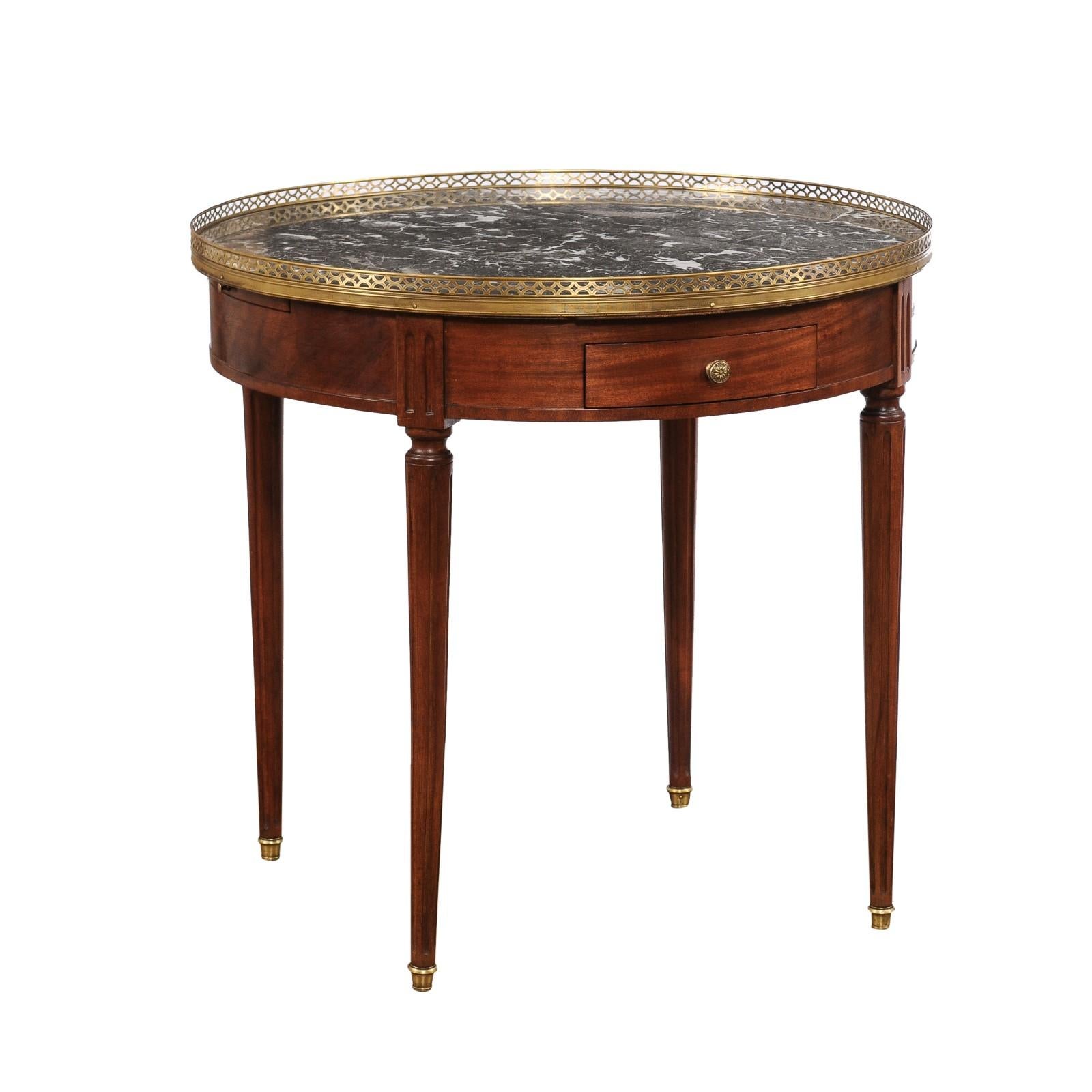 A French Louis XVI style bouillotte table from the 20th century, with grey veined marble top, pierced brass gallery, drawers, pull-outs and fluted motifs. Created in France during the 20th century, this bouillotte table showcases the stylistic