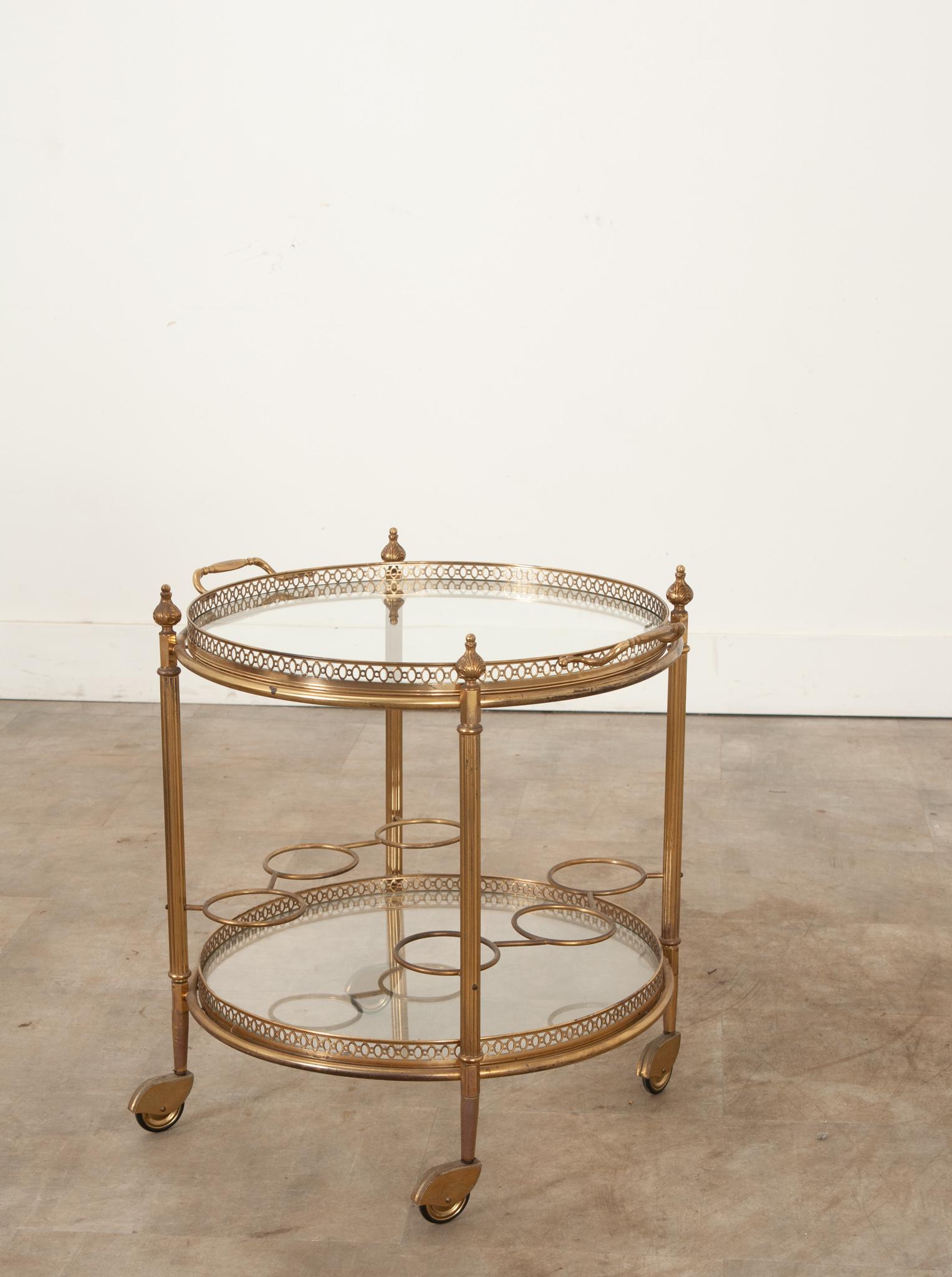 An elegant brass bar cart or trolley is the perfect occasional table for your interior. This rounded and tiered bar cart features two circular glass surfaces surrounded with pierced brass galleries. The top tier doubles as a removable serving tray