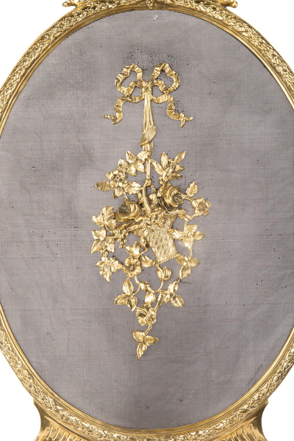 A good quality late 19th century French brass fire screen, having ribbon and scrolling foliate decoration, with a basket of flowers to the centre and raised on out swept scrolling feet.