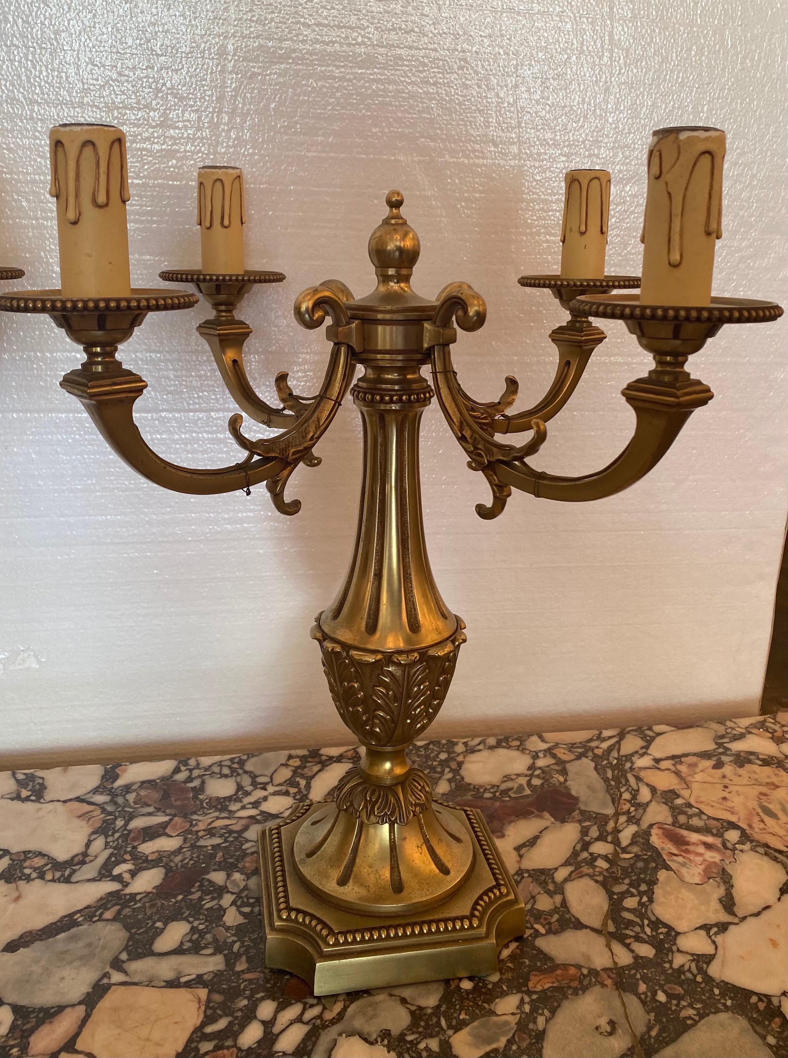 French Louis XVI style bronze candelabras, mid 20th c., fluted standard issuing four scrolled arms, each ending in beaded bobéches and faux candle, rising on a square base.