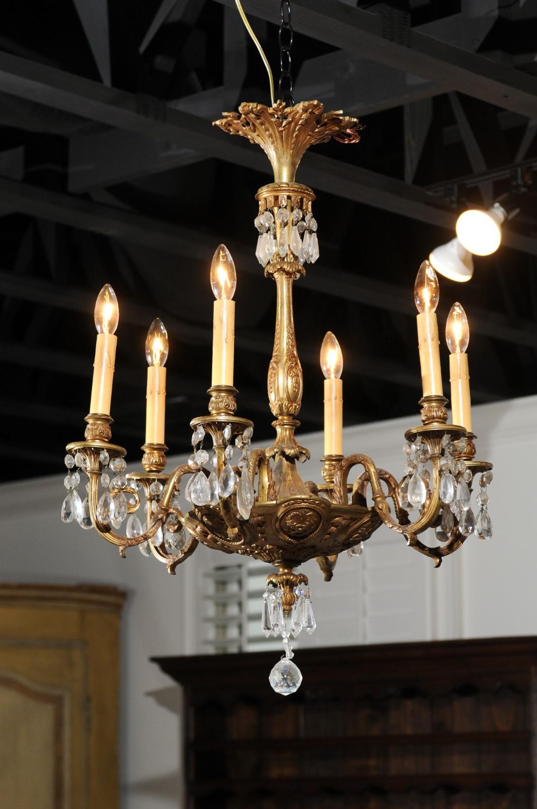 A French Louis XVI style bronze and crystal six-light chandelier from the 19th century, with foliage and medallion motifs. Born in France during the 19th century, this exquisite bronze chandelier features a central column adorned with foliage