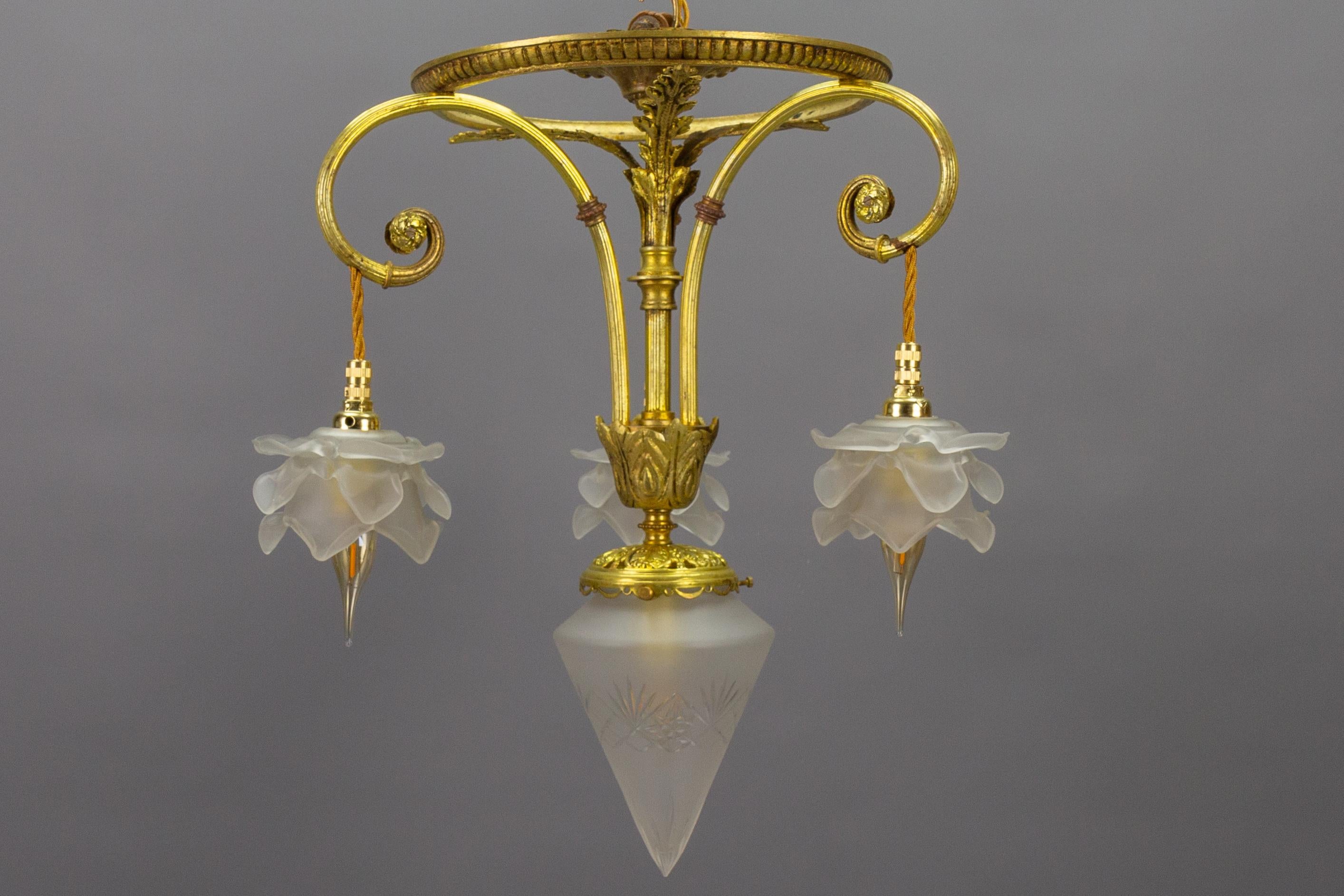 French Louis XVI style bronze and frosted cut glass four-light pendant chandelier from circa 1920s.
This adorable Neoclassical or Louis XVI-style bronze chandelier is adorned with scrolls, and acanthus leaves and features three beautifully shaped