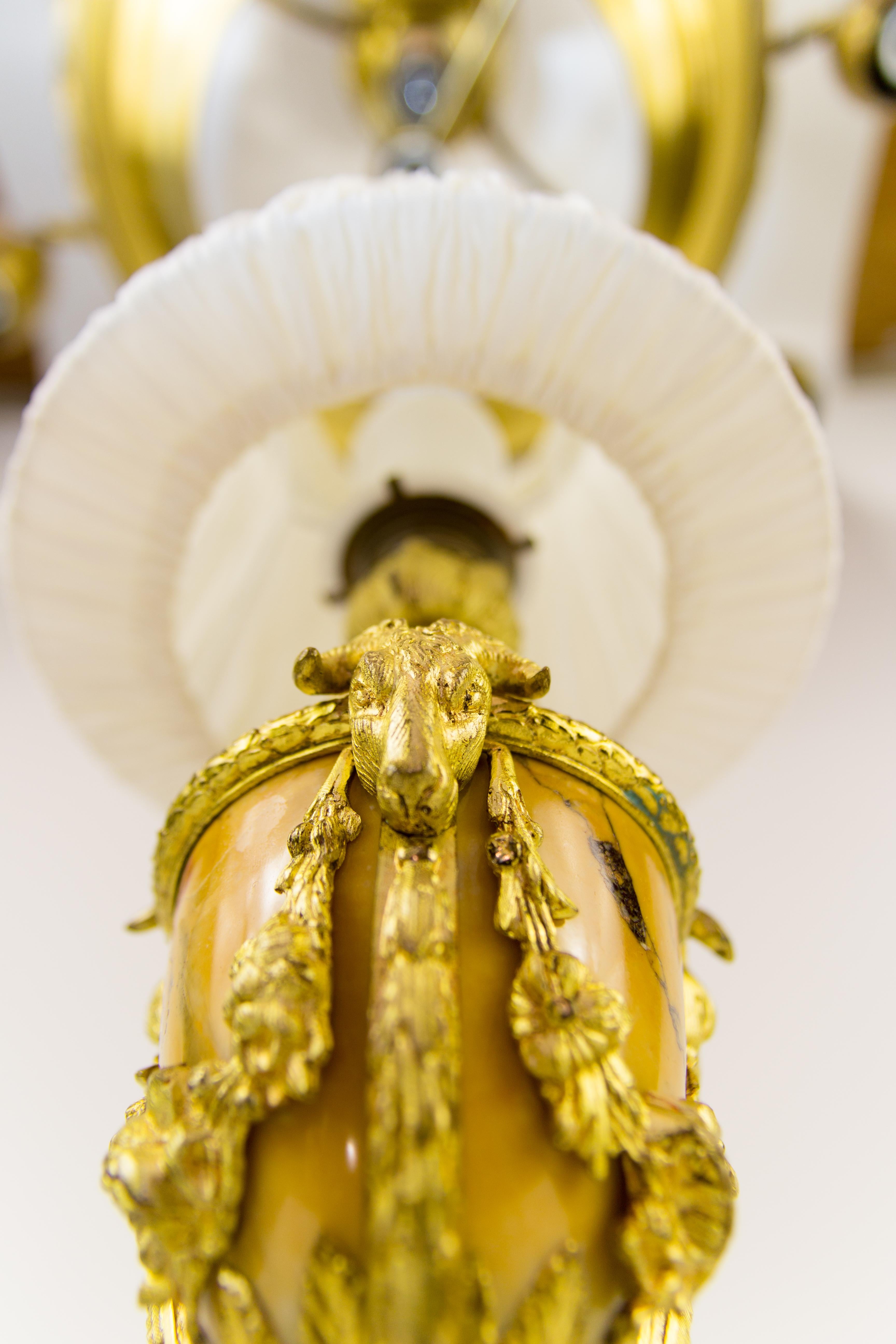 Antike französische Tischlampe aus Bronze und Marmor im Louis-XVI-Stil aus den 1920er Jahren mit Blumengirlanden und Widderköpfen. 
Auf drei Huffüßen auf einem dreieckigen Bronzesockel stehend. 
Diese schöne antike Tischlampe hat eine originale