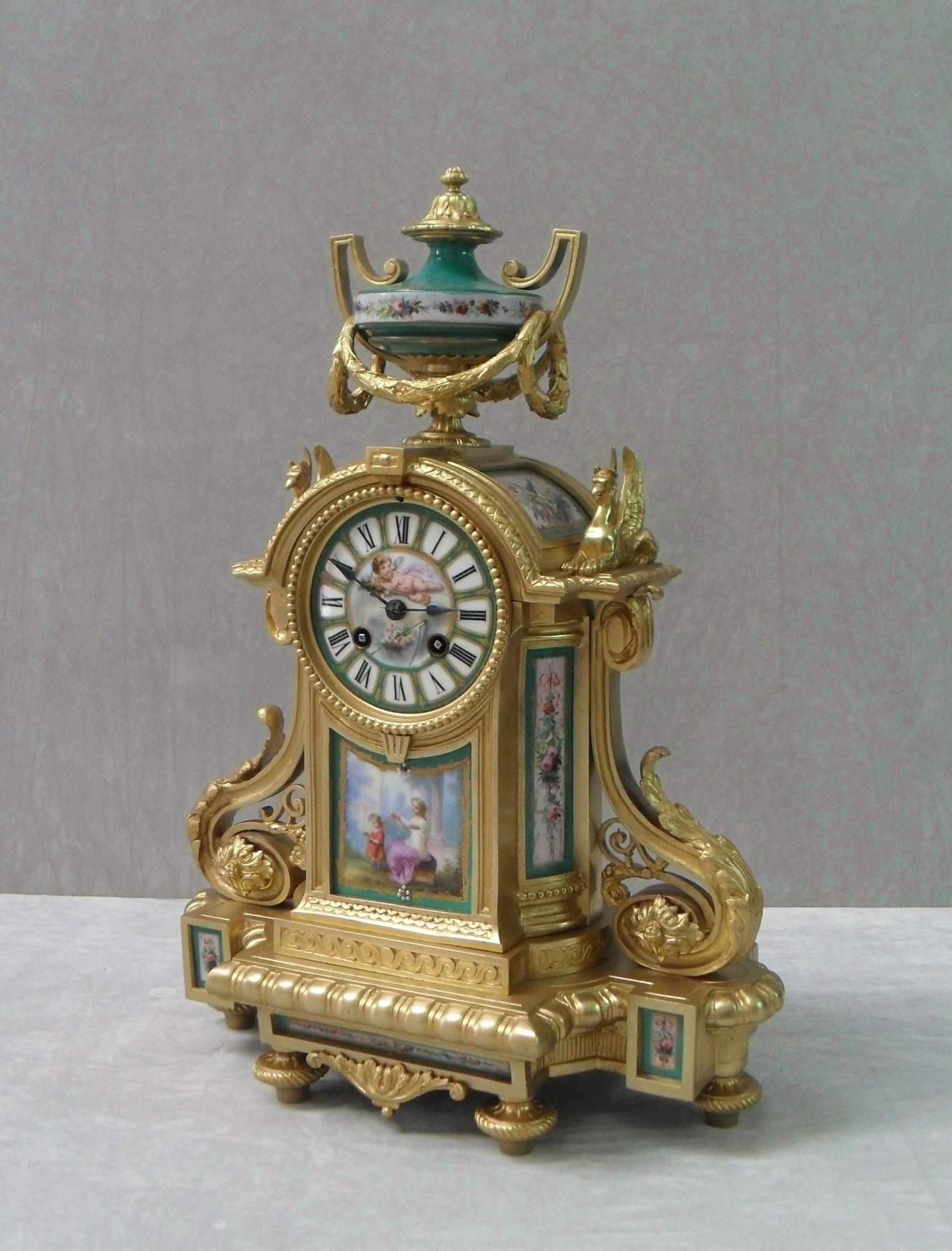 An excellent quality French Louis XVI style bronze gilt mantel clock with bowed sides, moulded edges and scrolling design finished with two griffins and urn to the top. The clock has delicately hand-painted porcelain Sevré style panels of flowers,