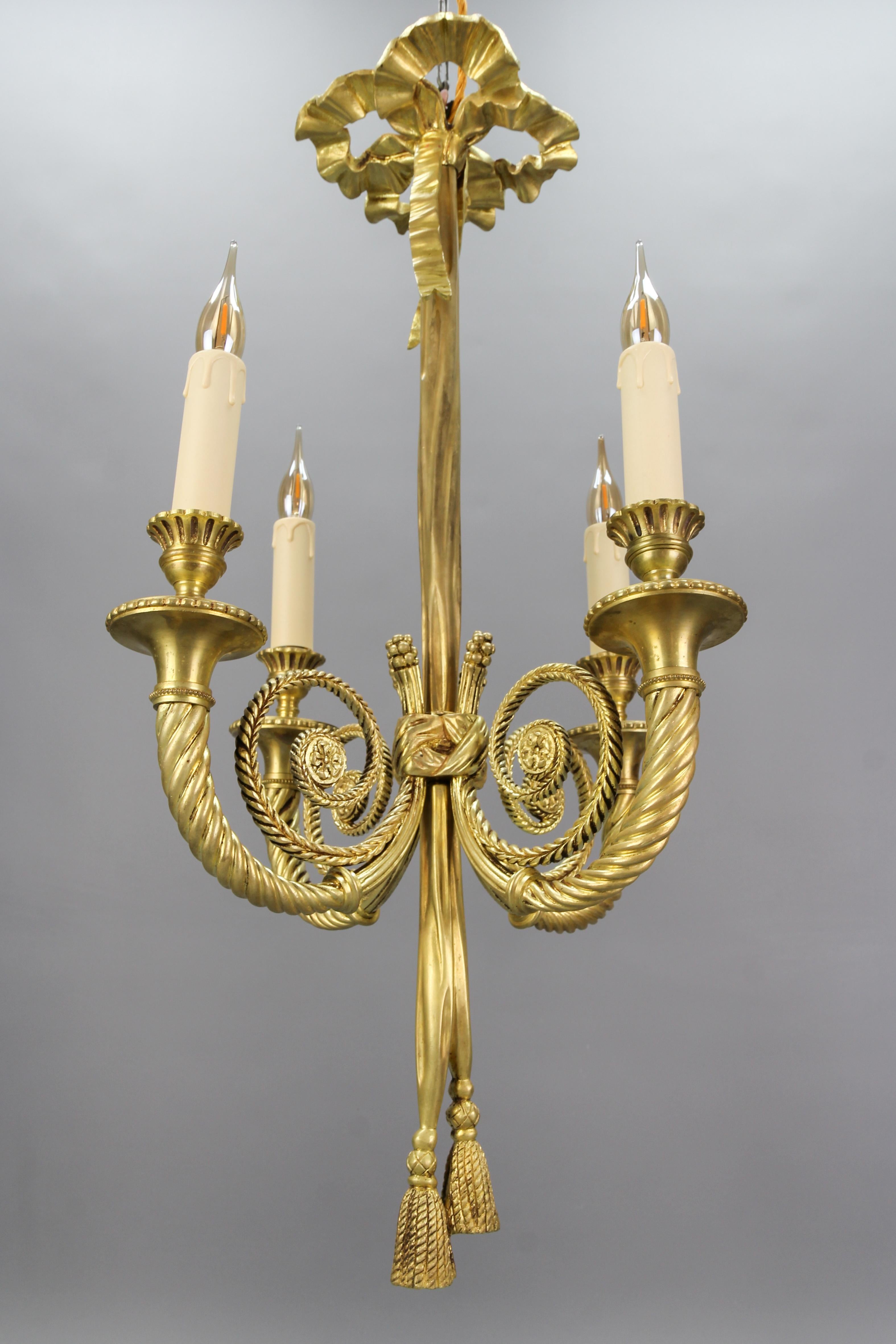 French Louis XVI style bronze four-light bow, ribbon, and tassel chandelier from the early 20th century.
An elegant Louis XVI or Neoclassical style bronze four-arm chandelier in the shape of knotted ribbons, with a bow on top, ending in tassels and