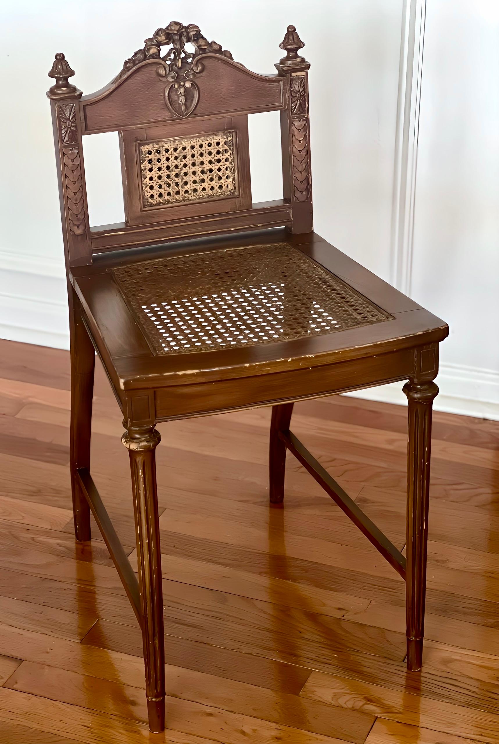 French Louis XVI style caned seat and back carved oak vanity chair, c. 1920.

Charming chair beautifully carved with central rosettes, ribbon swag, acanthus leaf finials and scrolled details. It is set upon fluted tapered front legs and shapely back