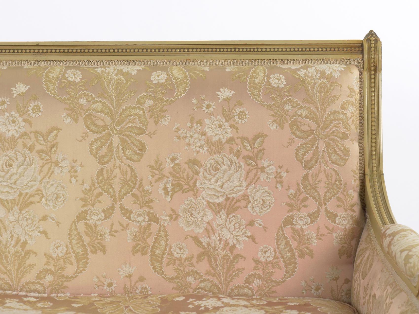 A gorgeous loveseat sofa from the second quarter of the 20th century, this iconic form is beautifully completed in the traditional Louis XVI form. Flanking the straight crest rail are a pair of small finials with draped laurel leaves over the crisp