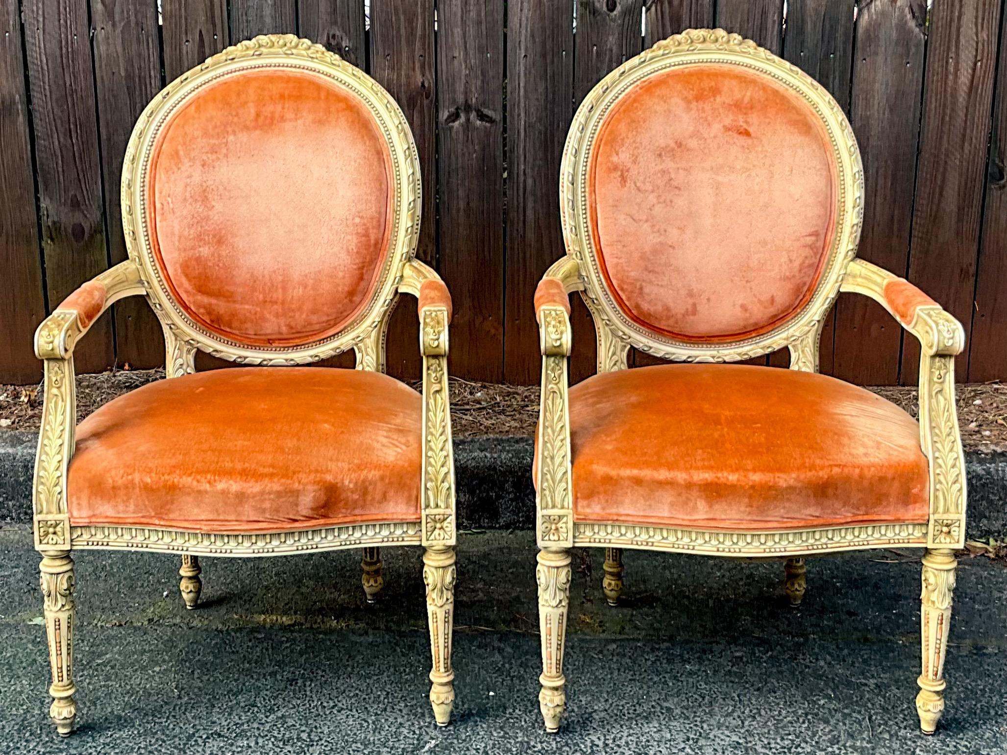 This is a nicely carved French Louis XVI style bergere chairs in original velvet. I believe they date to the 1940s or 50s. The frame is painted in an antique ivory and is in very good condition. The velvet shows wear. They are unmarked. Arm; 25.75”.