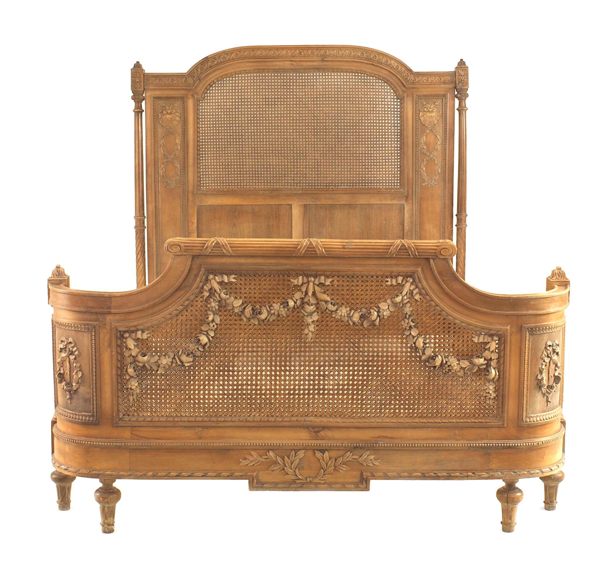 Turn of the century French Louis XVI style walnut full size bed with a cane panel headboard and footboard with rounded sides and a center cane panel with a carved festoon design with rails.