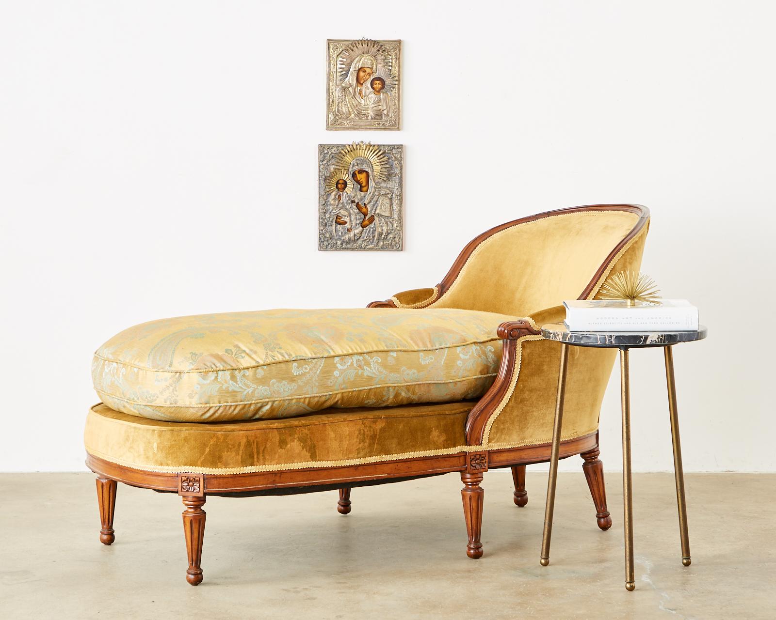 Gorgeous French mahogany chaise longue daybed made in the Louis XVI taste. The frame features a gracefully curved back ending with padded arms and scrolled ends. The lounge has been upholstered with velvet fabric and topped with an oversized loose