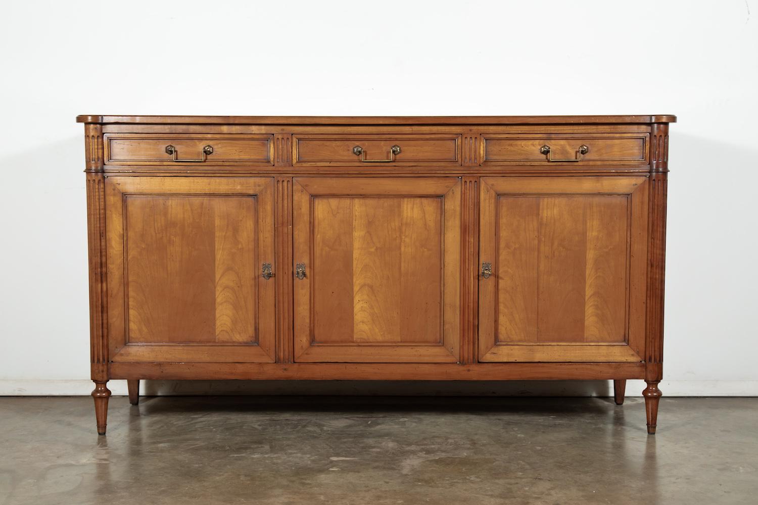 Handsome, French, Louis XVI style solid cherrywood enfilade buffet from the Brittany region, having three drawers with drop bail handles over four panelled doors. This extremely attractive enfilade with its straight lines and warm patina features