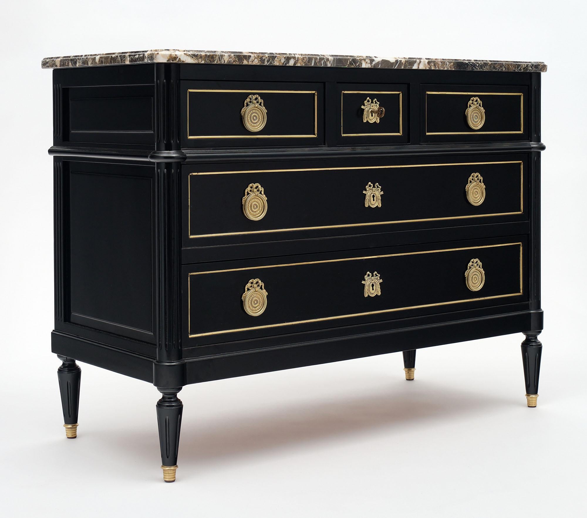 Chest or “commode” from France made of mahogany that has been ebonized and finished with a lustrous museum quality French polish finish. It features finely cast bronze hardware and a Turquin intact marble top. There are two dovetailed drawers below