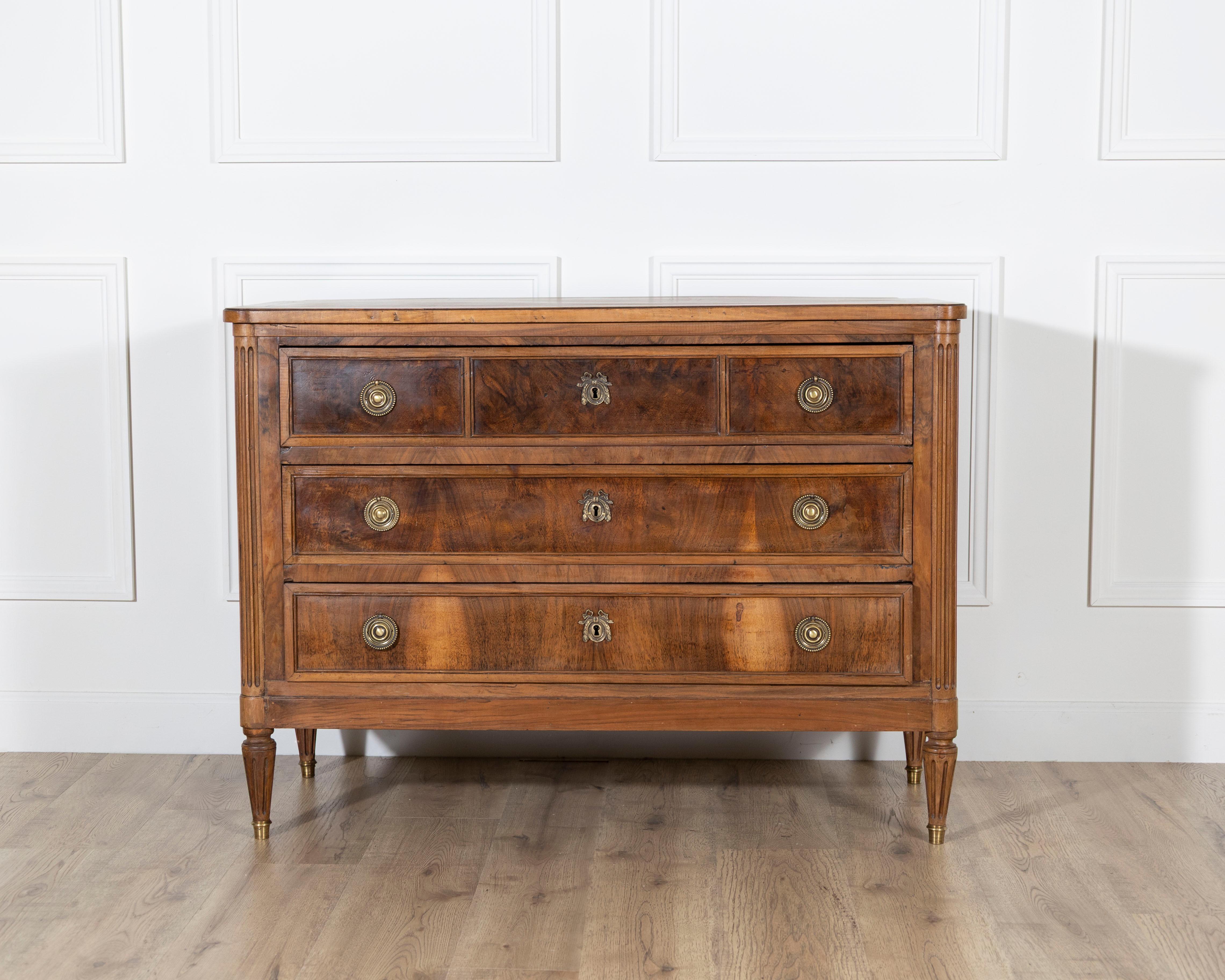 Questa raffinata cassettiera francese in stile Luigi XVI, risalente al 1920 circa, è un pezzo dalle splendide proporzioni che rende omaggio all'eleganza neoclassica della fine del XVIII secolo. Realizzata in noce riccamente sgranato, la facciata
