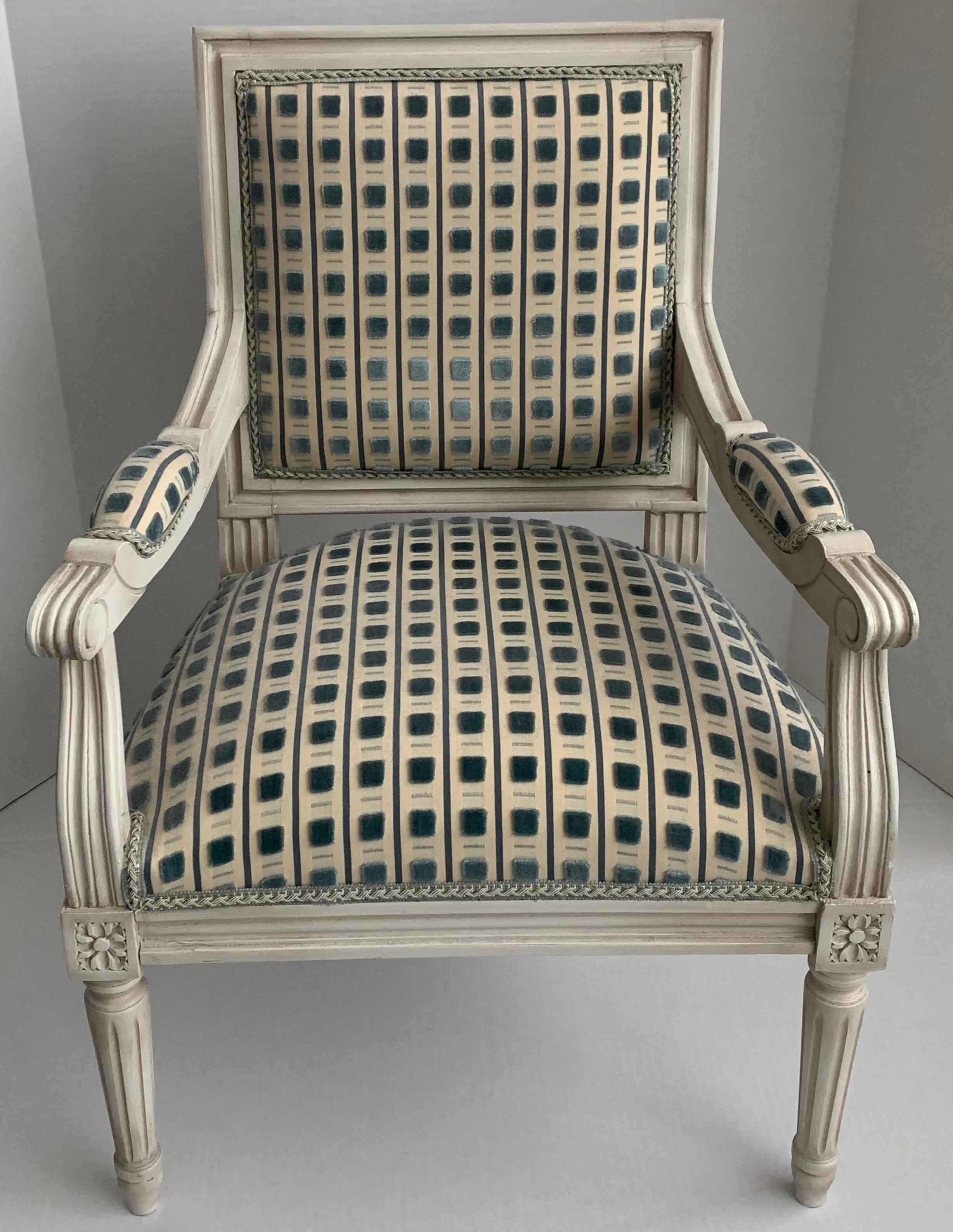 Custom made French Louis XVI style children’s size armchair. Painted in a cream colored antique finish and upholstered in Scalamandre “Pitti” cut velvet in blue on cream background. Braided tape trim to match. Chair back is upholstered in