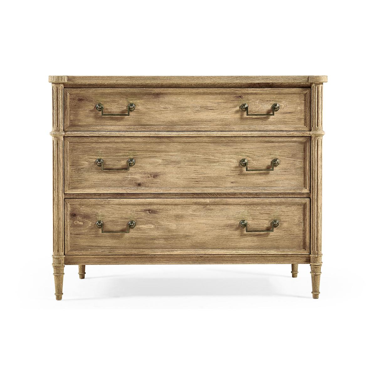 French Louis XVI Style Commode, made with chestnut in a natural stripped finish that marries effortlessly with custom-cast hardware. Turret corners, fluted styles, three long drawers and turned and tapered legs. A versatile piece that elevates both