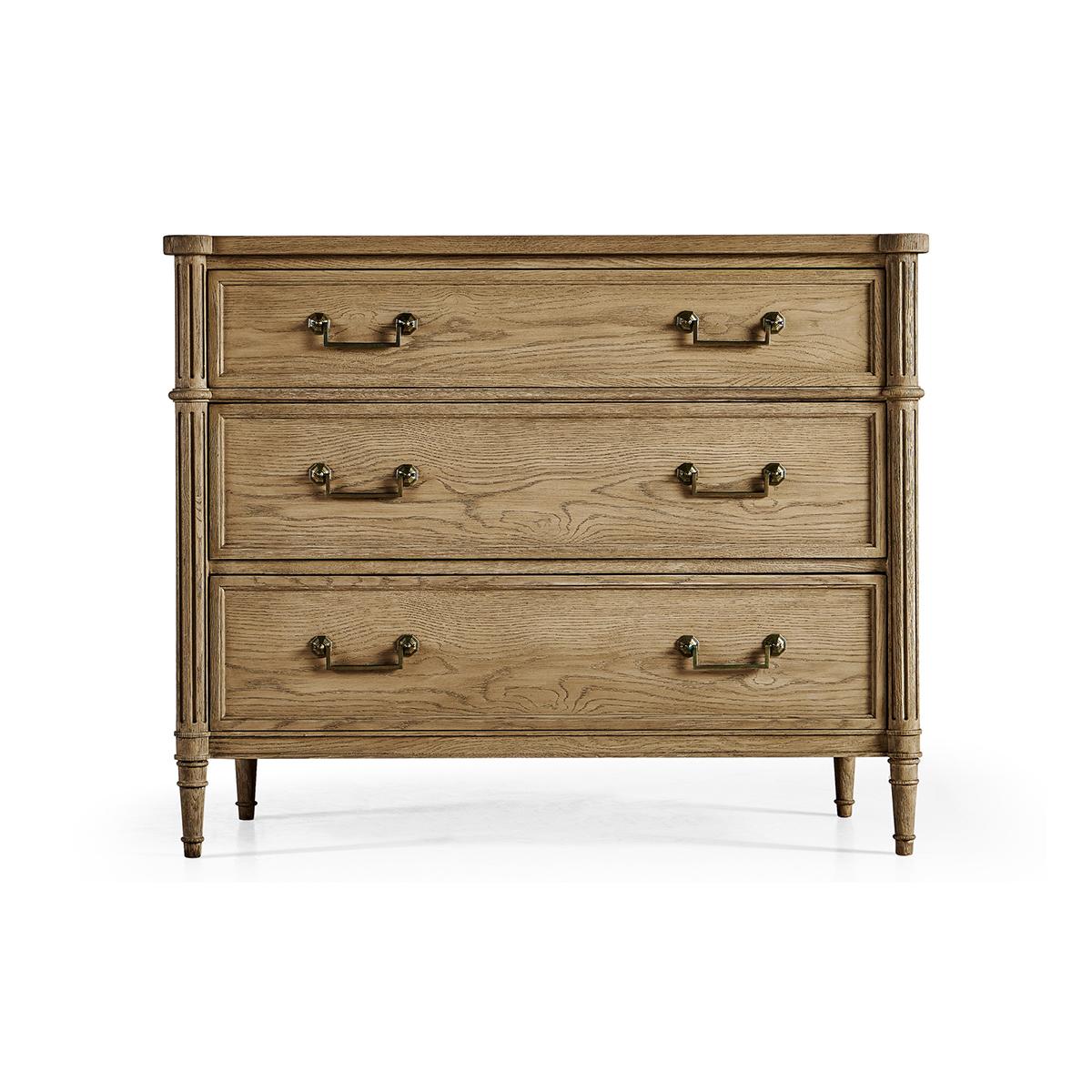 French Louis XVI style Commode, made with chestnut in a natural stripped finish that marries effortlessly with custom-cast hardware. Turret corners, fluted styles, three long drawers and turned and tapered legs. A versatile piece that elevates both