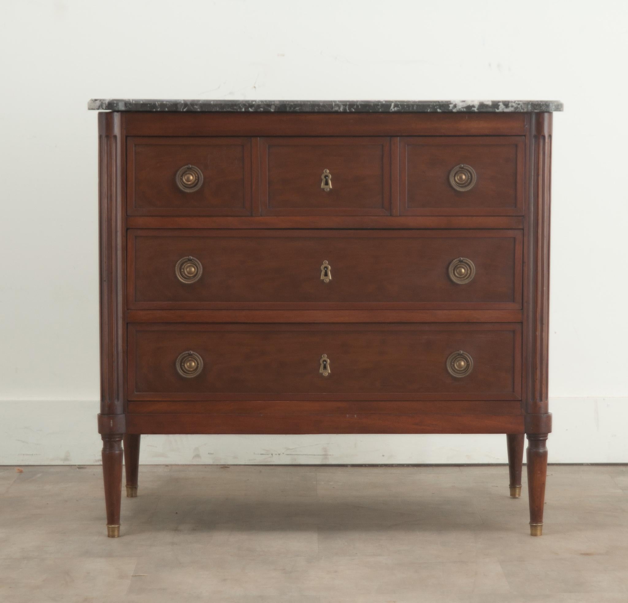 A petite French Louis XVI style mahogany and marble commode. The original, shaped St. Anne’s marble top has been professionally repaired and makes for a gorgeous and durable surface. Three vertically stacked drawers are easy to use with brass pulls
