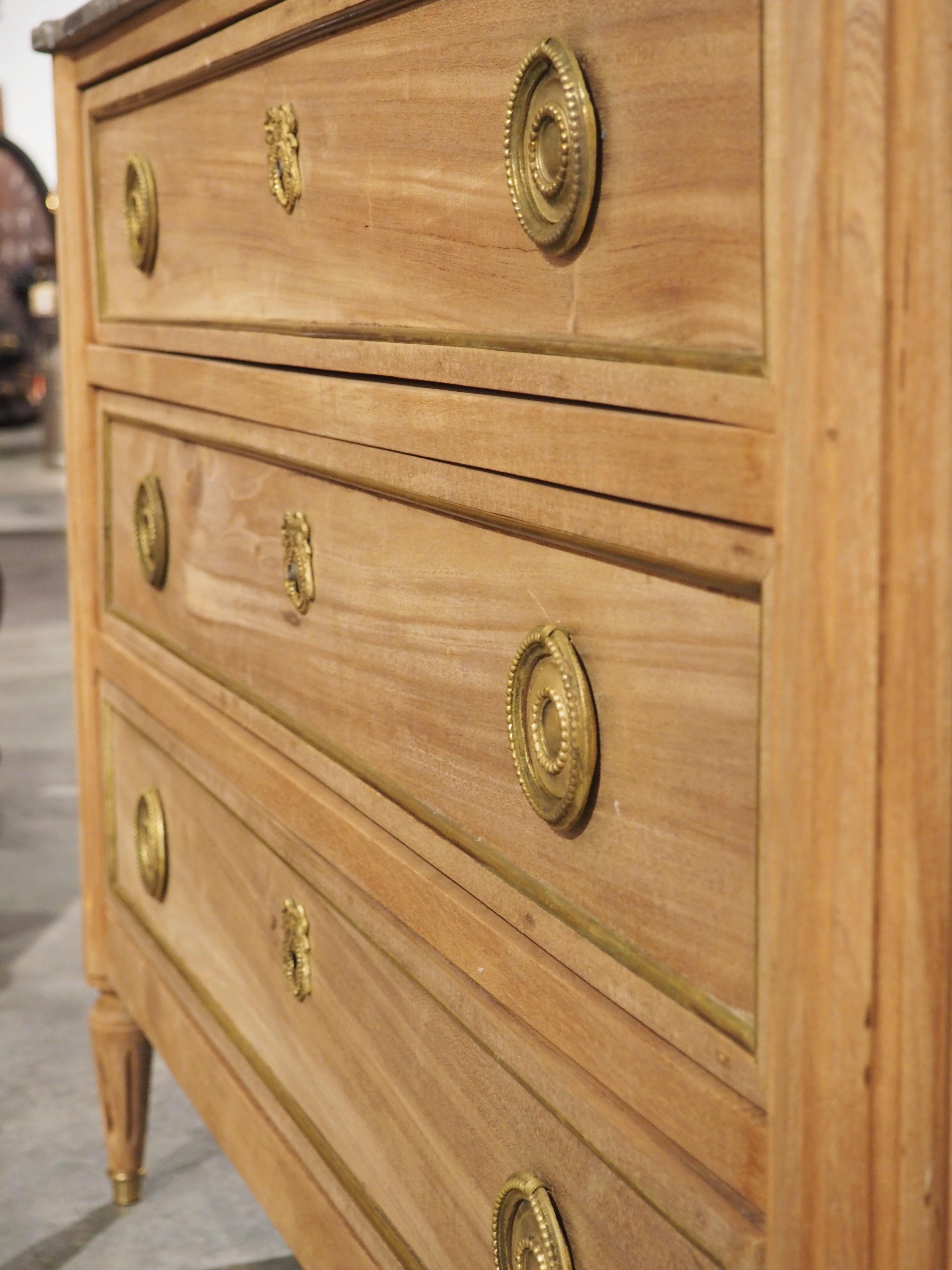 During the Louis XVI period, mahogany furniture became very fashionable since the wood was pleasing to work with and often featured beautiful grain patterns. The original finish of this Louis XVI style commode had been previously bleached, allowing