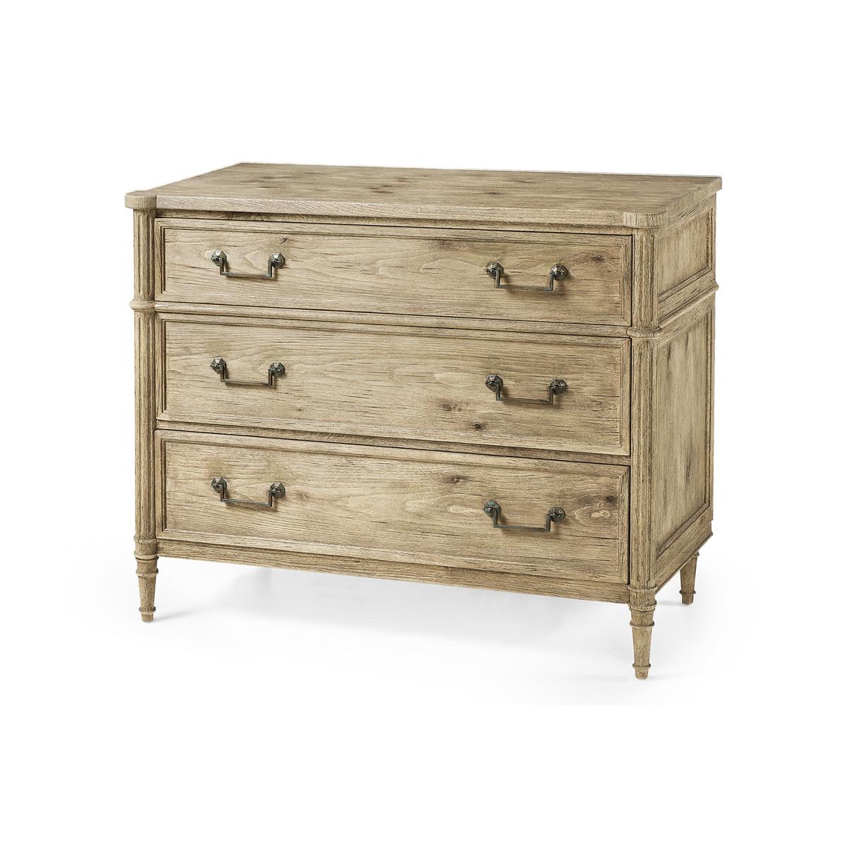 French Louis XVI Style Commode, made with chestnut in a natural bleached finish that marries effortlessly with custom-cast hardware. Turret corners, fluted styles, three long drawers and turned and tapered legs. A versatile piece that elevates both