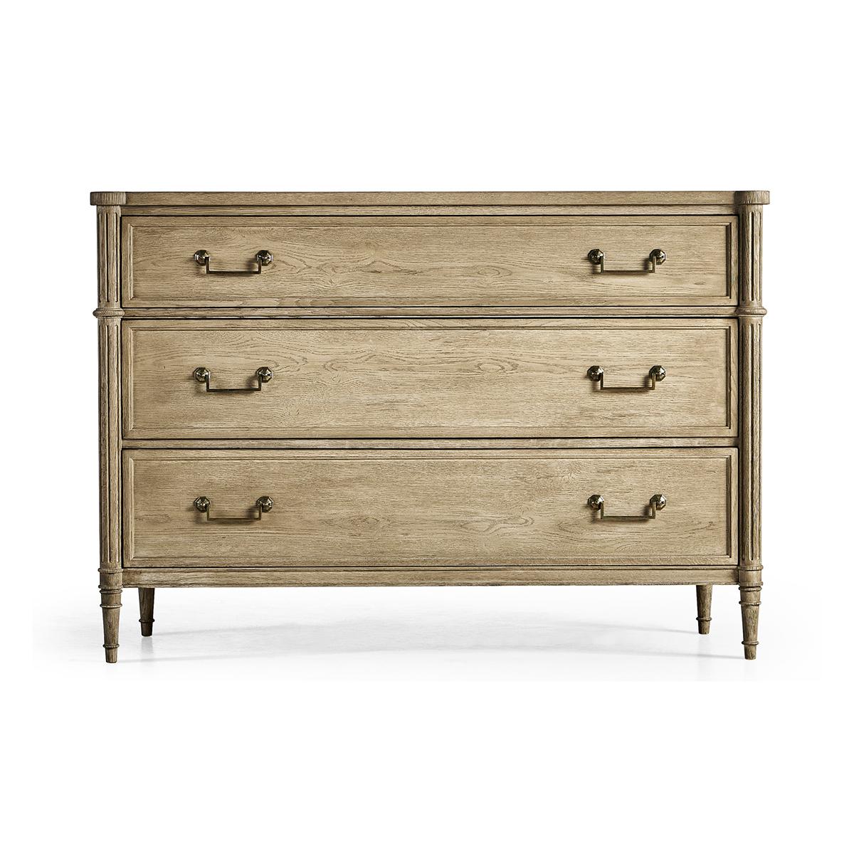 French Louis XVI Style Commode, made with chestnut in a natural stripped finish that marries effortlessly with custom-cast hardware. Turret corners, fluted styles, three long drawers and turned and tapered legs. A versatile piece that elevates both