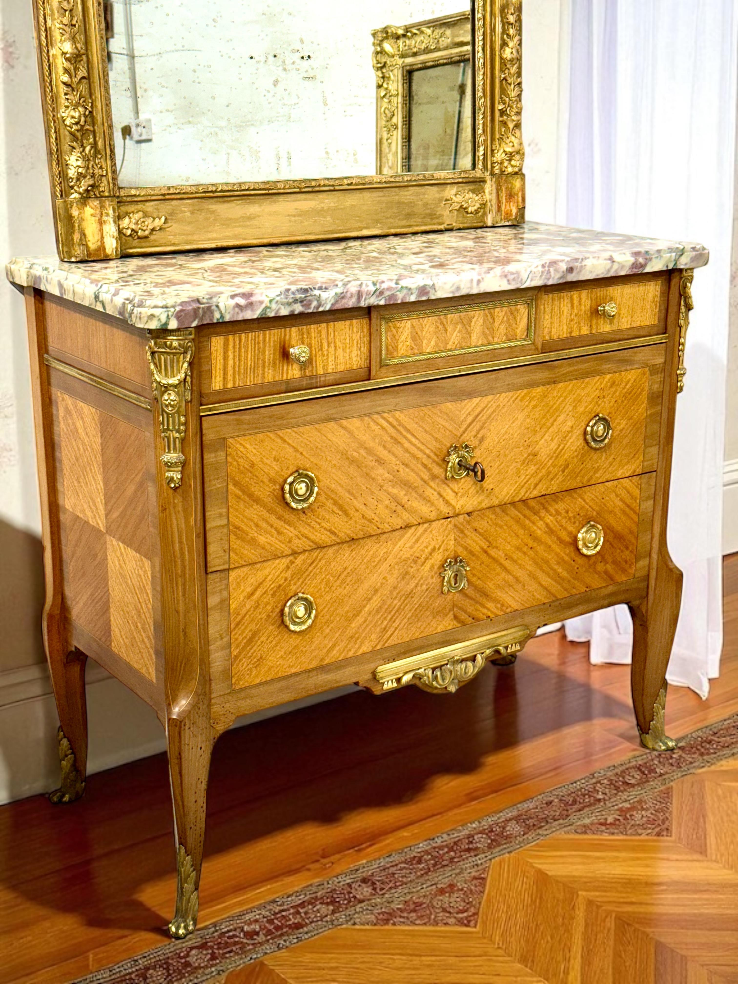 A refined 19th century French Louis XVI style commode, crafted with a beechwood structure and veneered in warm-toned walnut arranged in elegant chevron and quarter-turn patterns. This graceful piece features three drawers — two deep and one shallow