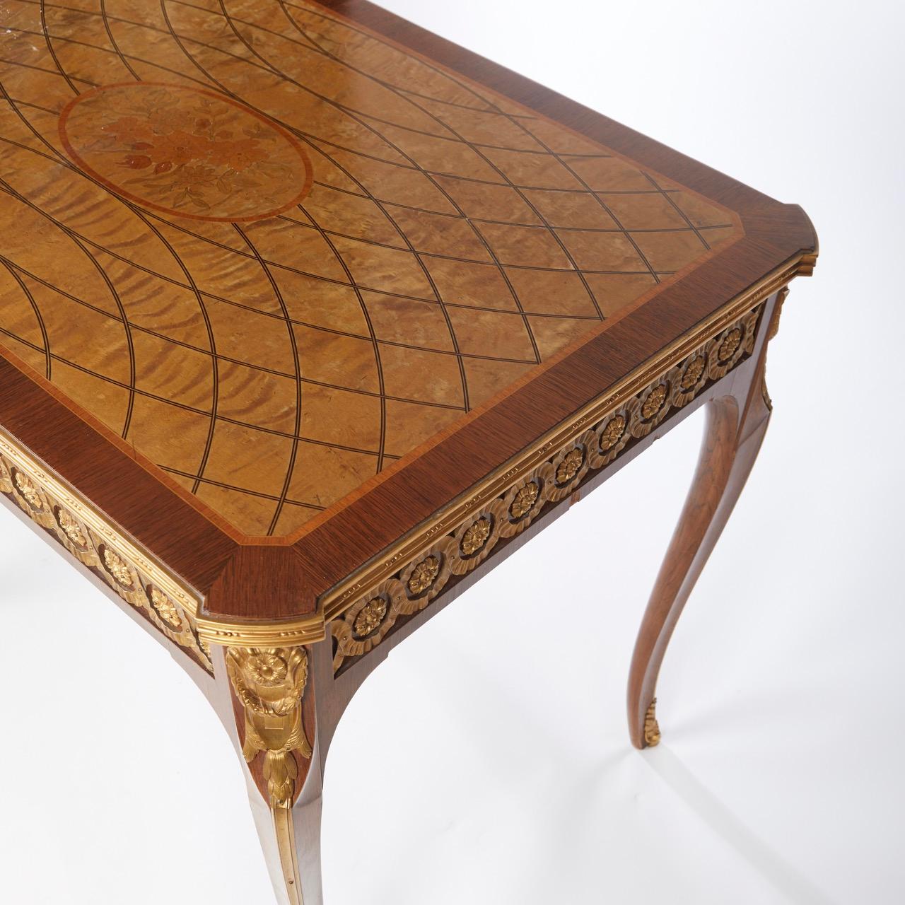 A French Louis XVI-style center table/console table. The apron with inset cast brass guilloché pattern frize below a marquetry inlaid top with bronze edge. The transitional-style legs (Louis XV-XVI) having bronze sabouxes. By Nordiska Kompaniet,