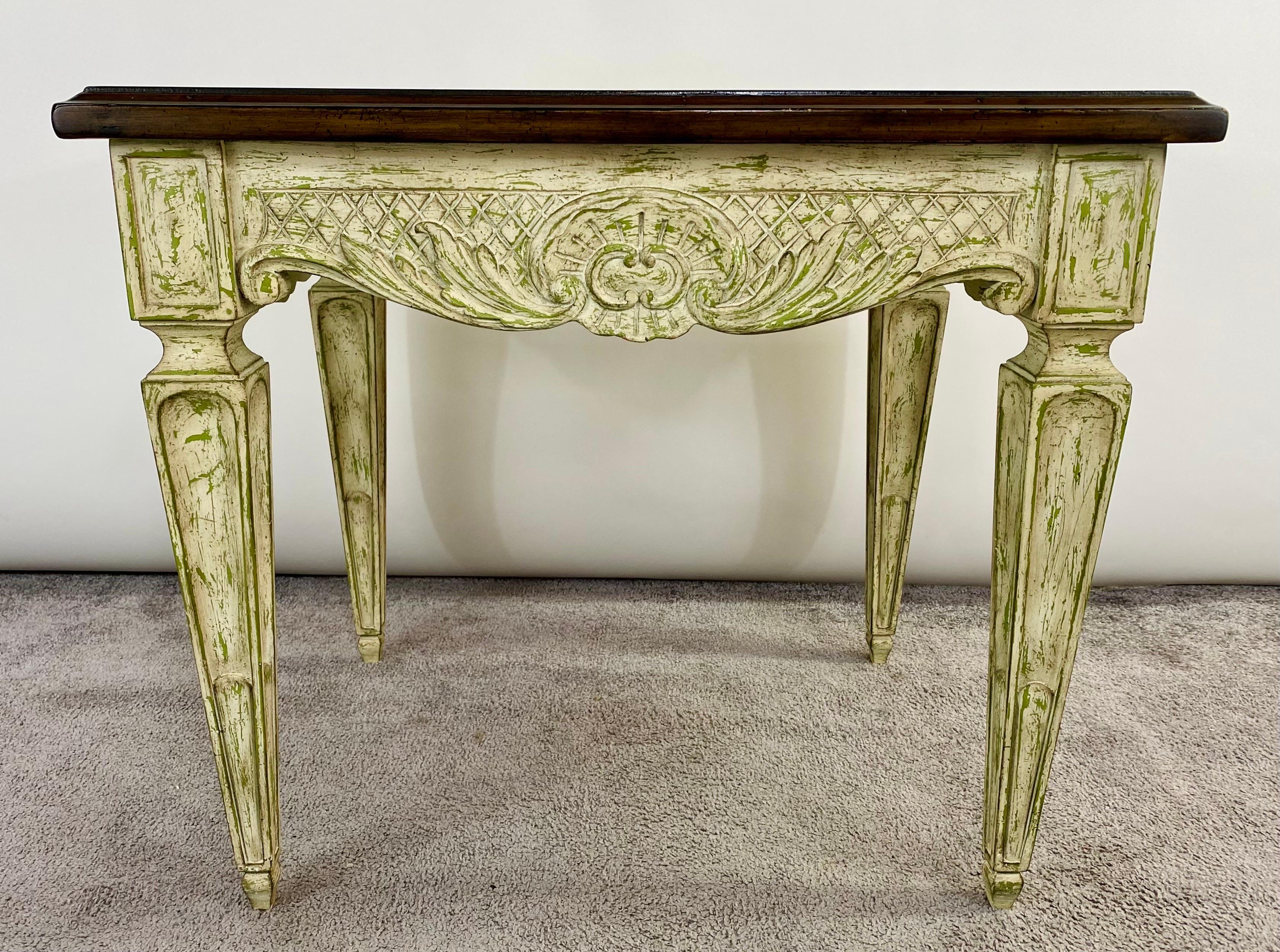A classy French Louis XVI style side or end table. Beautifully carved and showing floral and scroll design, the table has a solid mahogany top and is raised on four solid fluted legs in an inverted truncated pyramid shape. The table features a