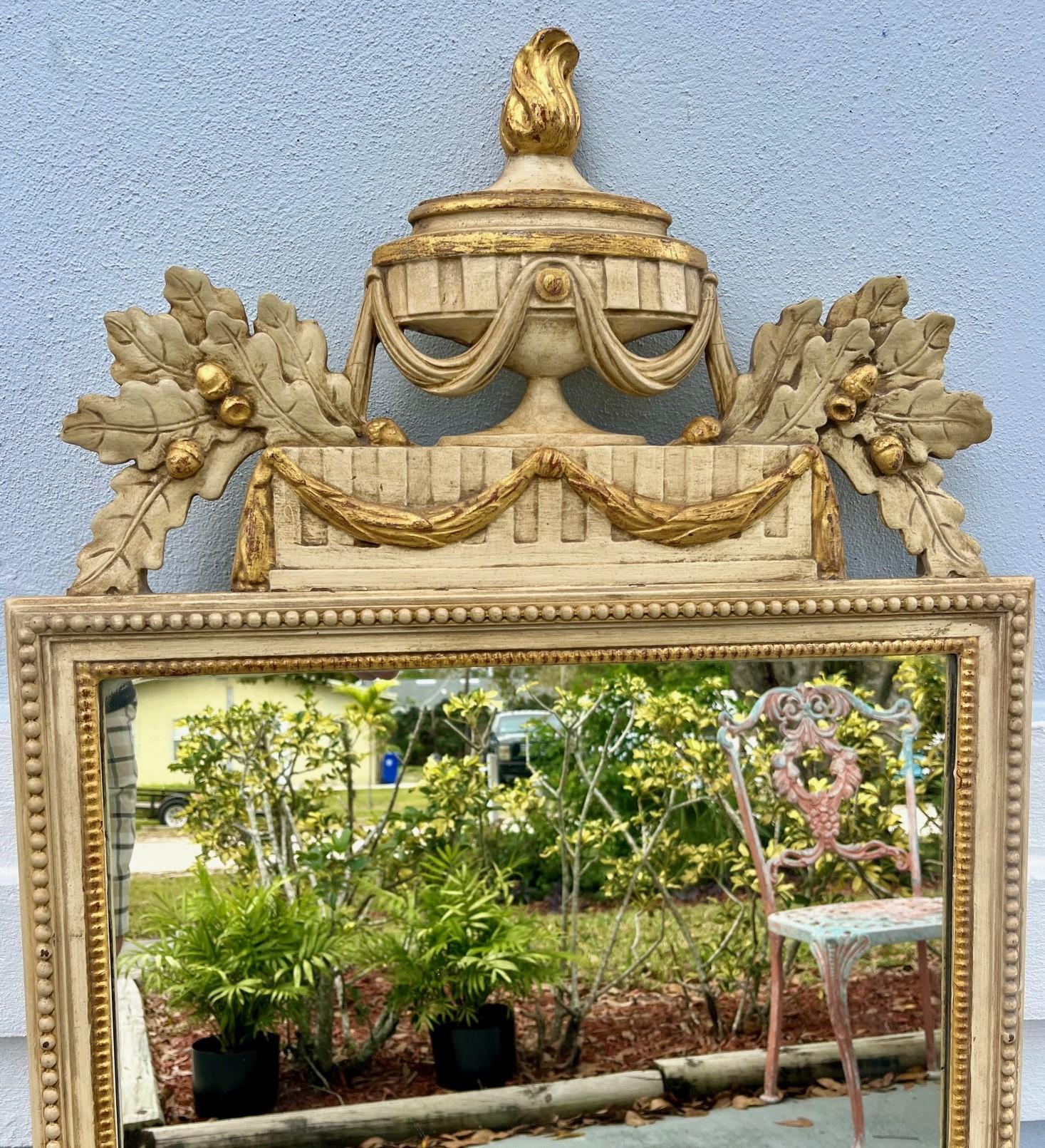 French Louis XVI Style Cream and Gilt Painted Wall Mirror

Elegant wall mirror with hand carved pediment. This piece is created in the early 20th century in France. The frame is beaded with gilt highlights. The pediment features a classical center