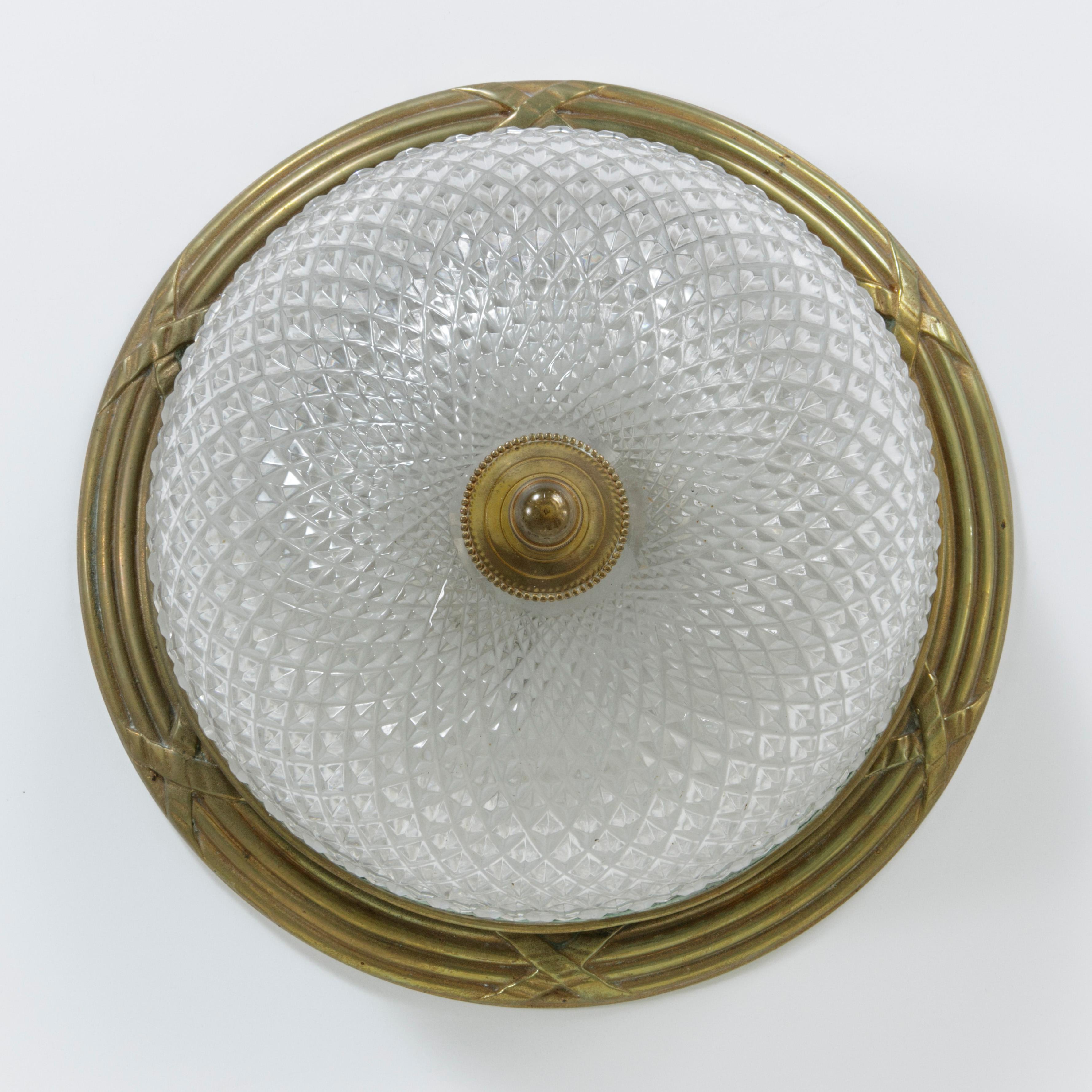This French flush mount ceiling light from the mid-20th century features a multifaceted crystal dome trimmed with a pierced gilt bronze gallery and held in place with a bronze acorn finial. The rim around the mount is detailed with a Classic Louis