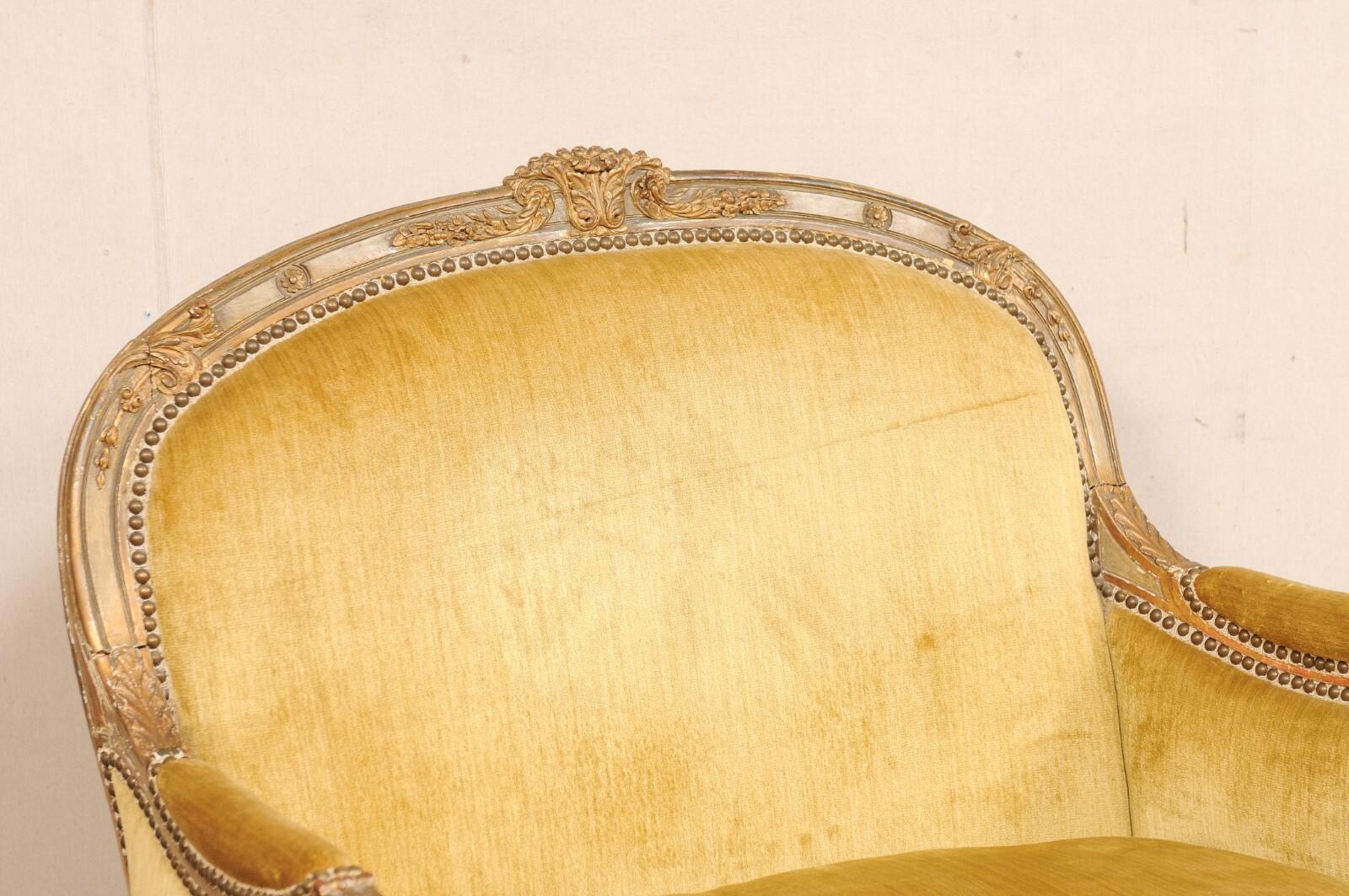 A French Louis XVI style marquise with cut-velvet and nail-head trim. This vintage settee from France has a softly arched back and bowed shape at front, it showcases the Louis XVI decorative vocabulary with tightly scrolled knuckles, petite flower
