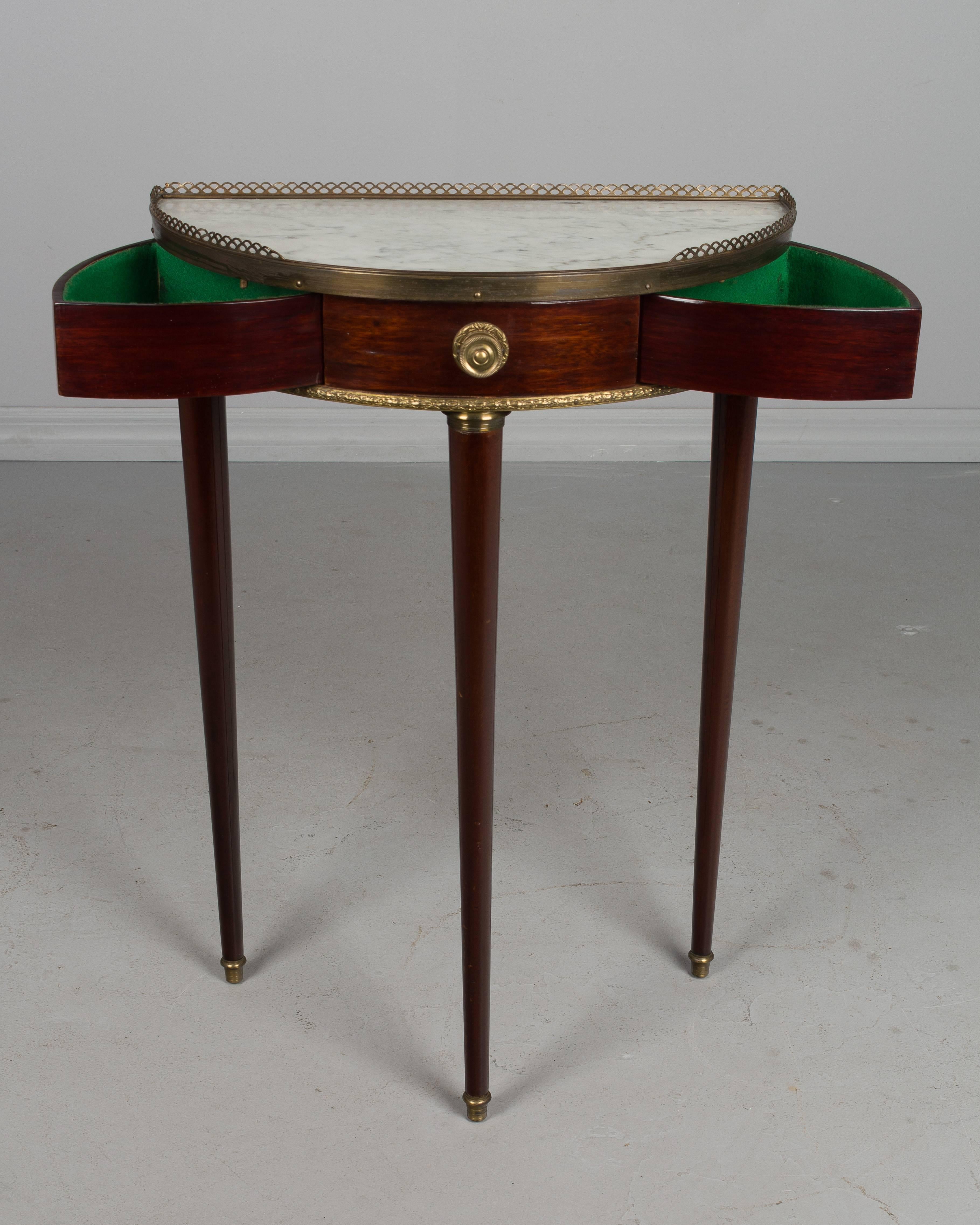 A small French mahogany demilune console table with white marble top and brass gallery. Two felt lined drawers open by spring mechanism when the centre knob is pulled. An unusual and clever design. French Polish and in great condition.