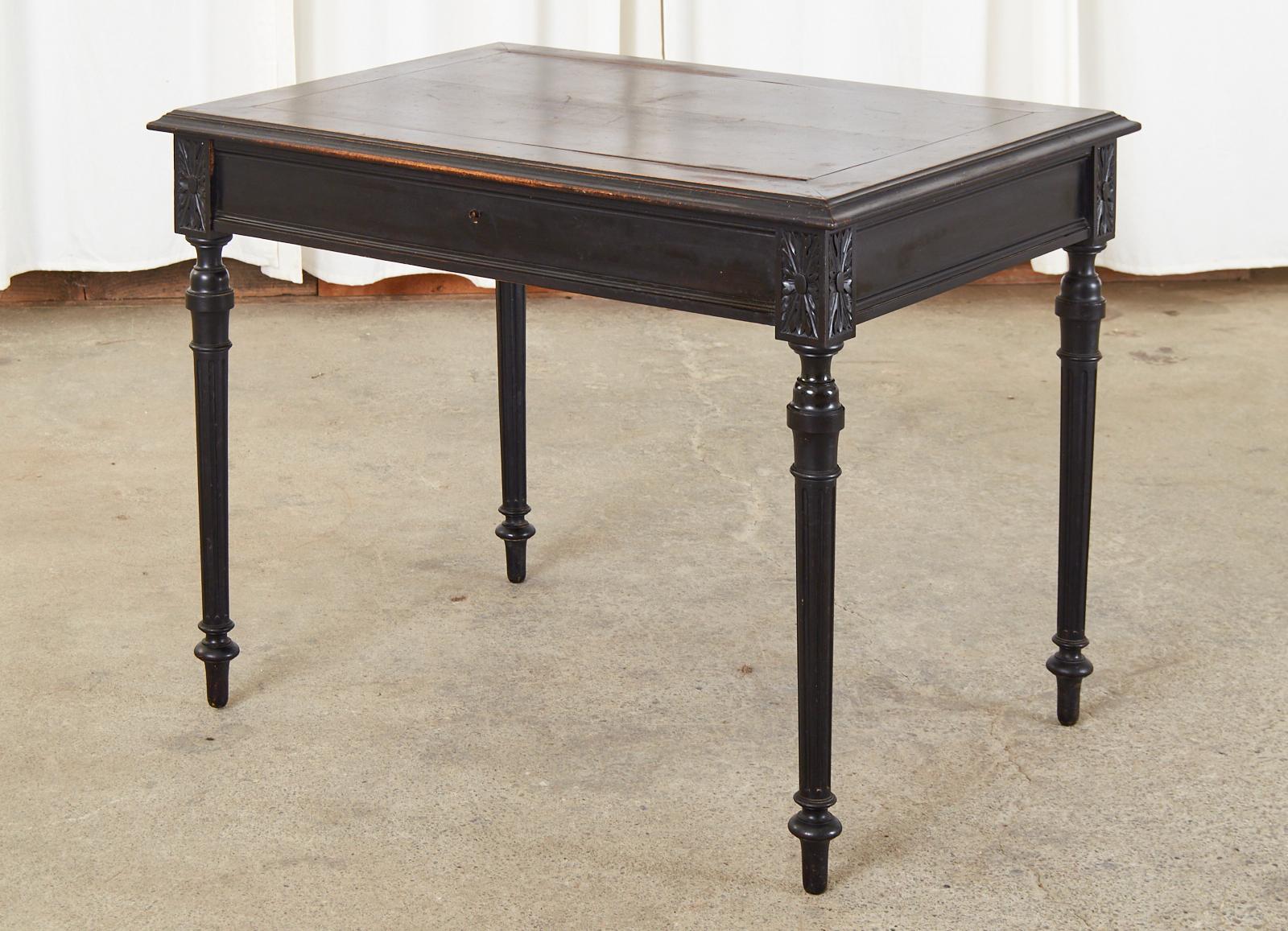 Dramatic French diminutive ladies writing table or desk featuring a black lacquer ebonized finish. Made in the neoclassical Louis XVI taste with a simple clean design and minimal decorative embellishments. The case has an ogee edge on the top and is
