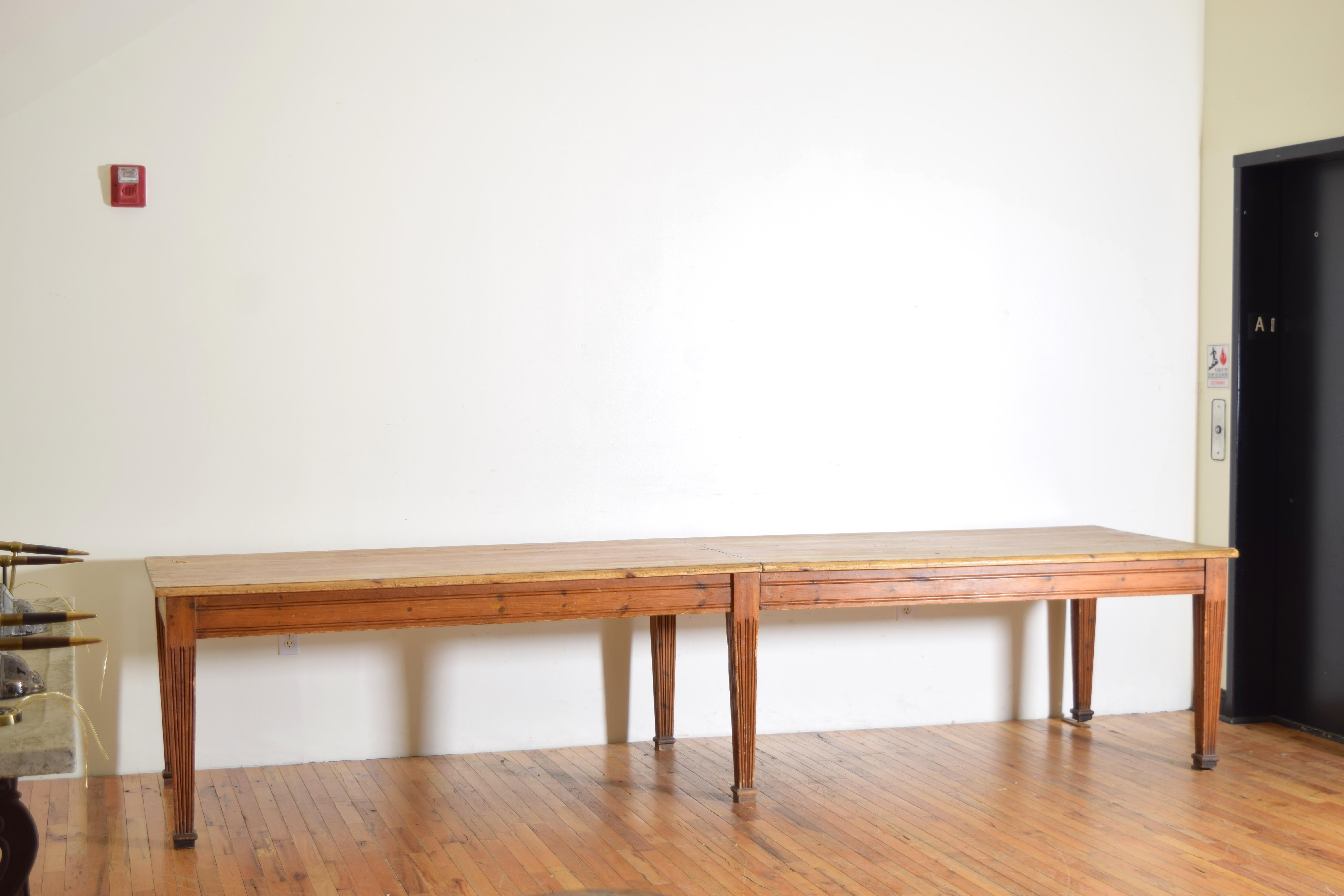 Very long table in two sections the top having a molded edge and straight apron, raised on tapering fluted legs ending in shaped feet