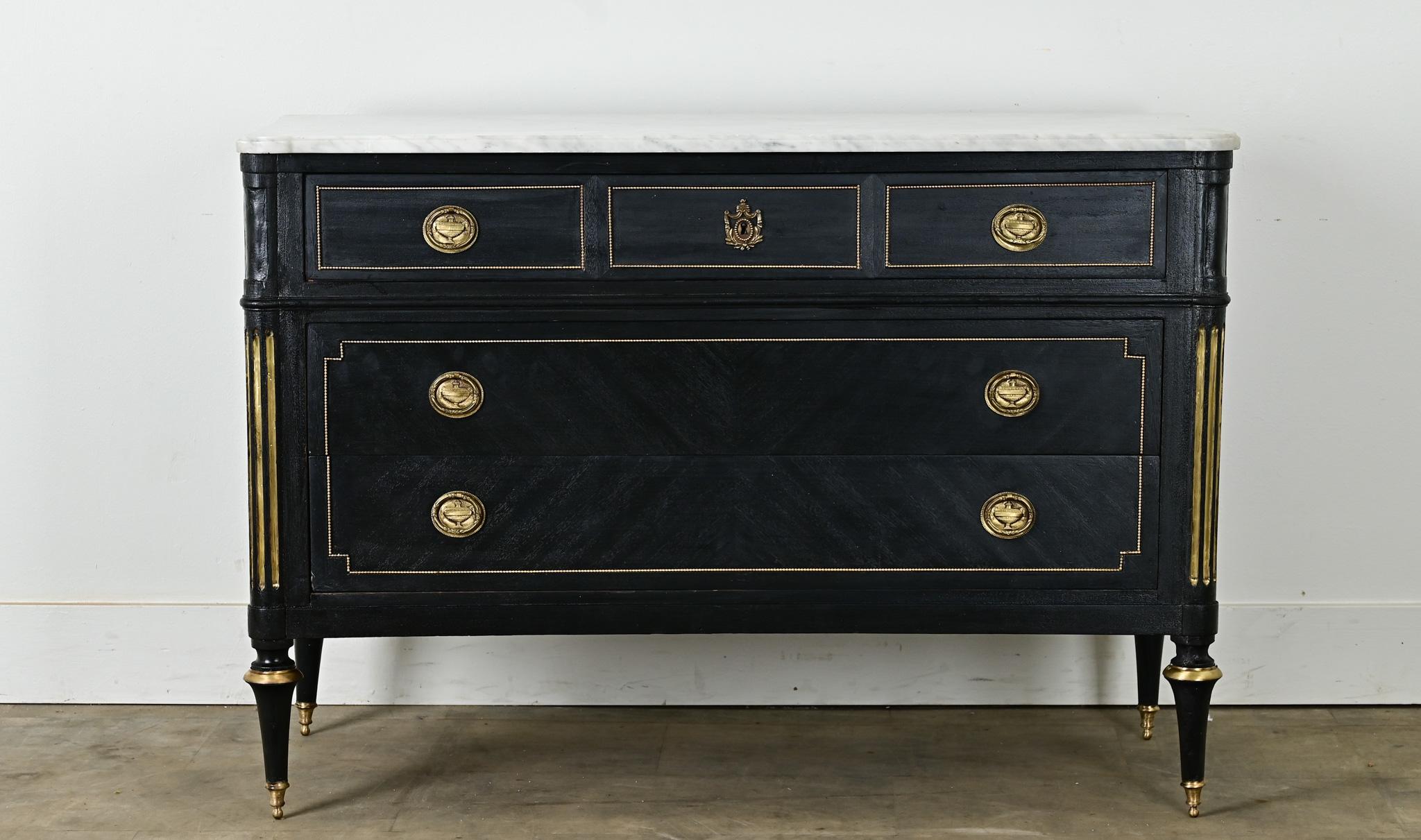 A 19th Century French commode in the Louis XVI Style has recently been painted black. The marble is original and hand cut to fit over its base with a worn polished finish. A pair of fluted columns flank three large paneled drawers. The drawers are