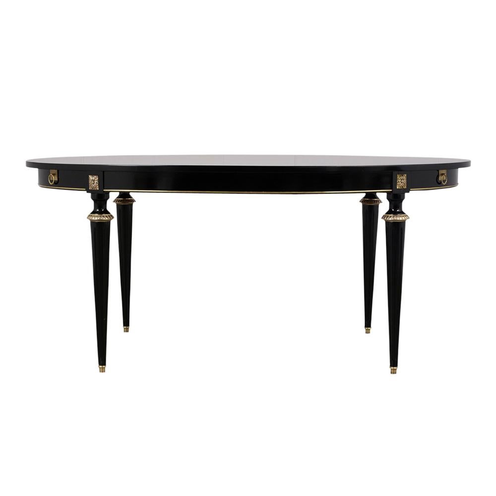 This Louis XVI style oval dining table has a beautiful ebonized finish. It also features gilt moldings along the edges and the carved legs have gilt accents and brass toe caps. The table comes with two extra leaves and two pairs of arms for added