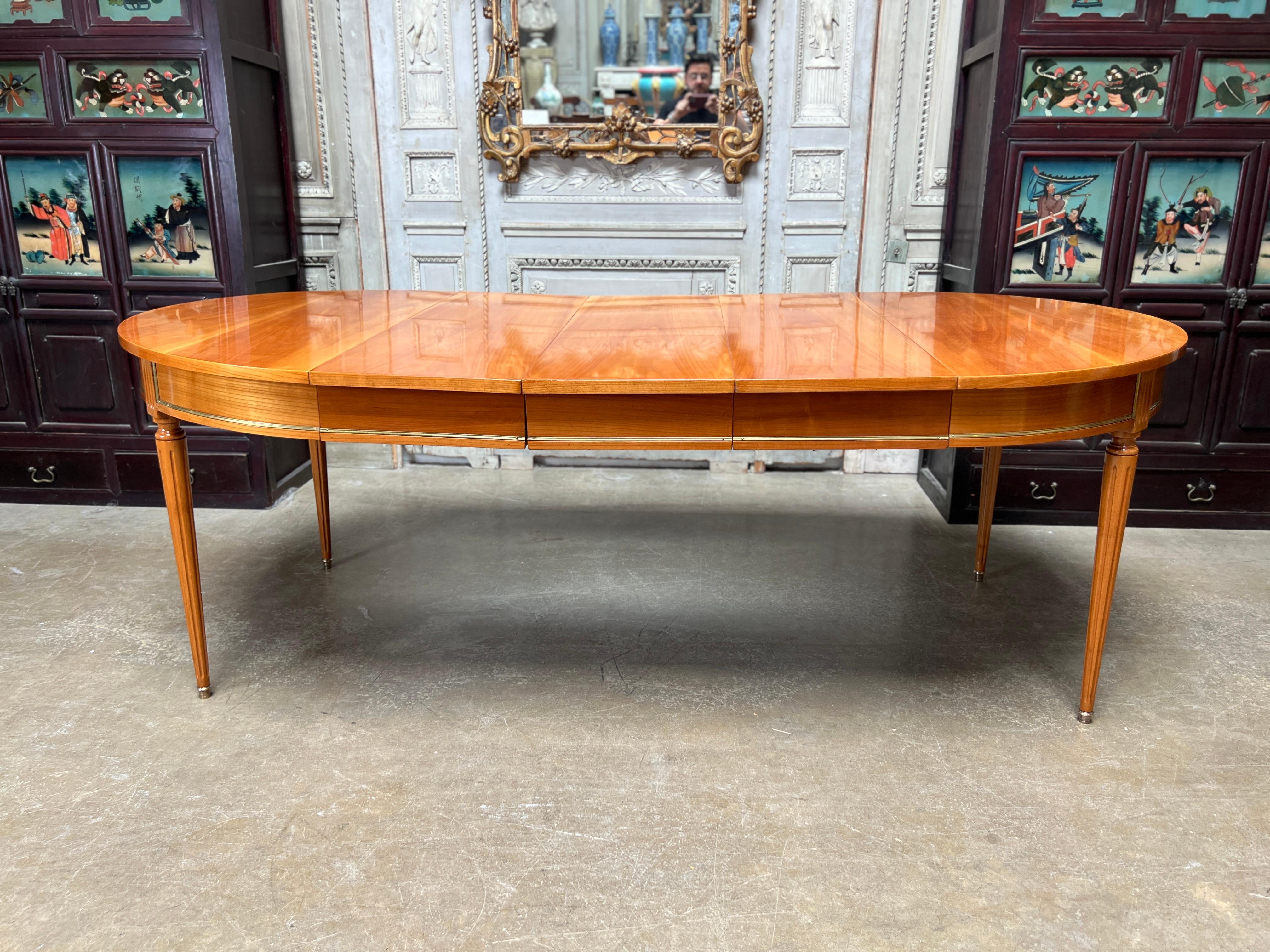 A French Louis XVI style extension cherrywood dining table with bronze molding.  This beautiful table is very versatile with three leaves with an apron that can be removed to make several different lengths.  It is a great size and wonderful warm