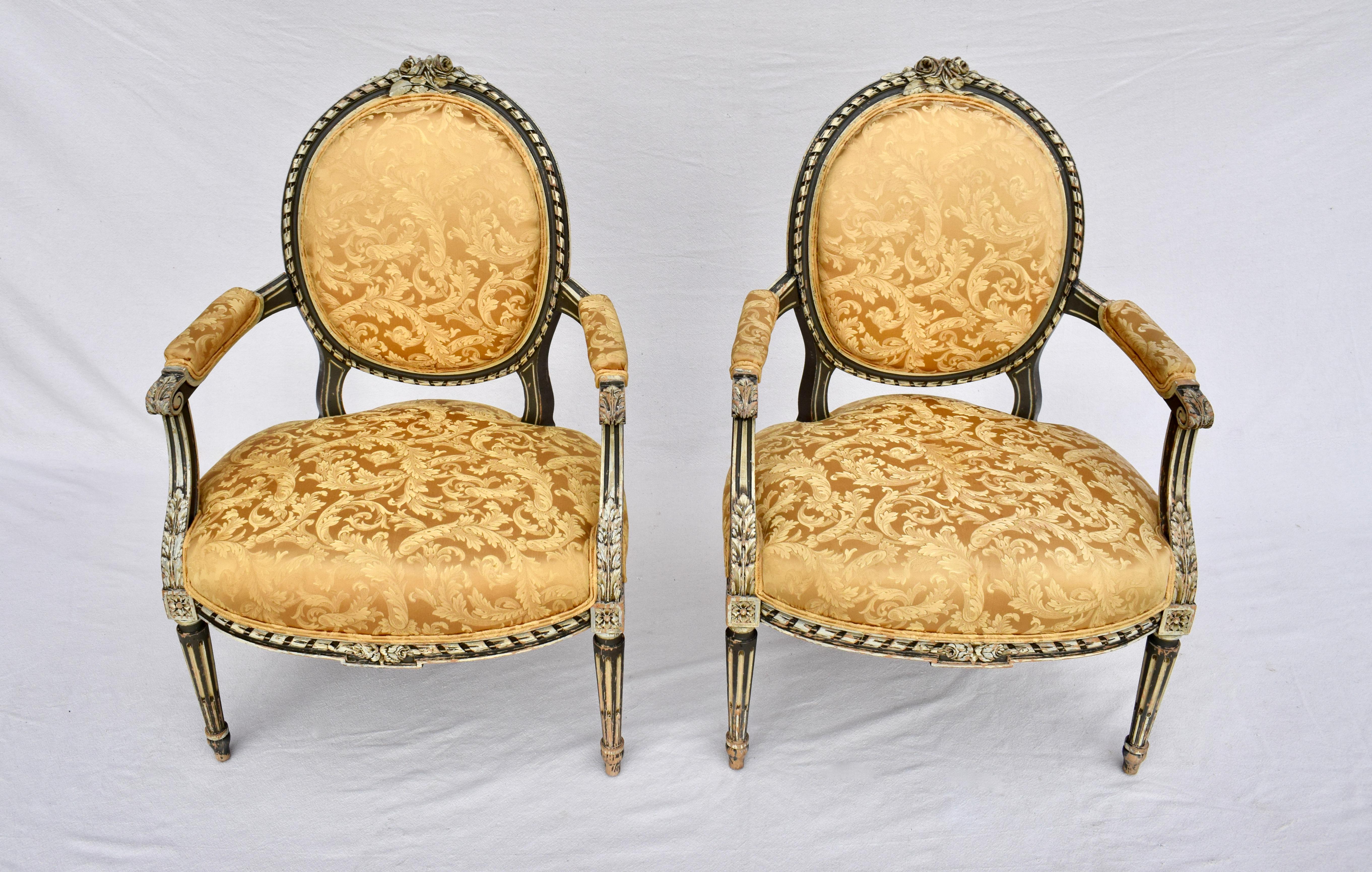 A pair of early 20th C. French Louis Xvi style open arm Fauteuils with exquisite carvings throughout and reinforced joinery. The Canary Gold Damask Upholstery is in lovely vintage condition with some signs of wear to the seats. Seat Height: 20.5