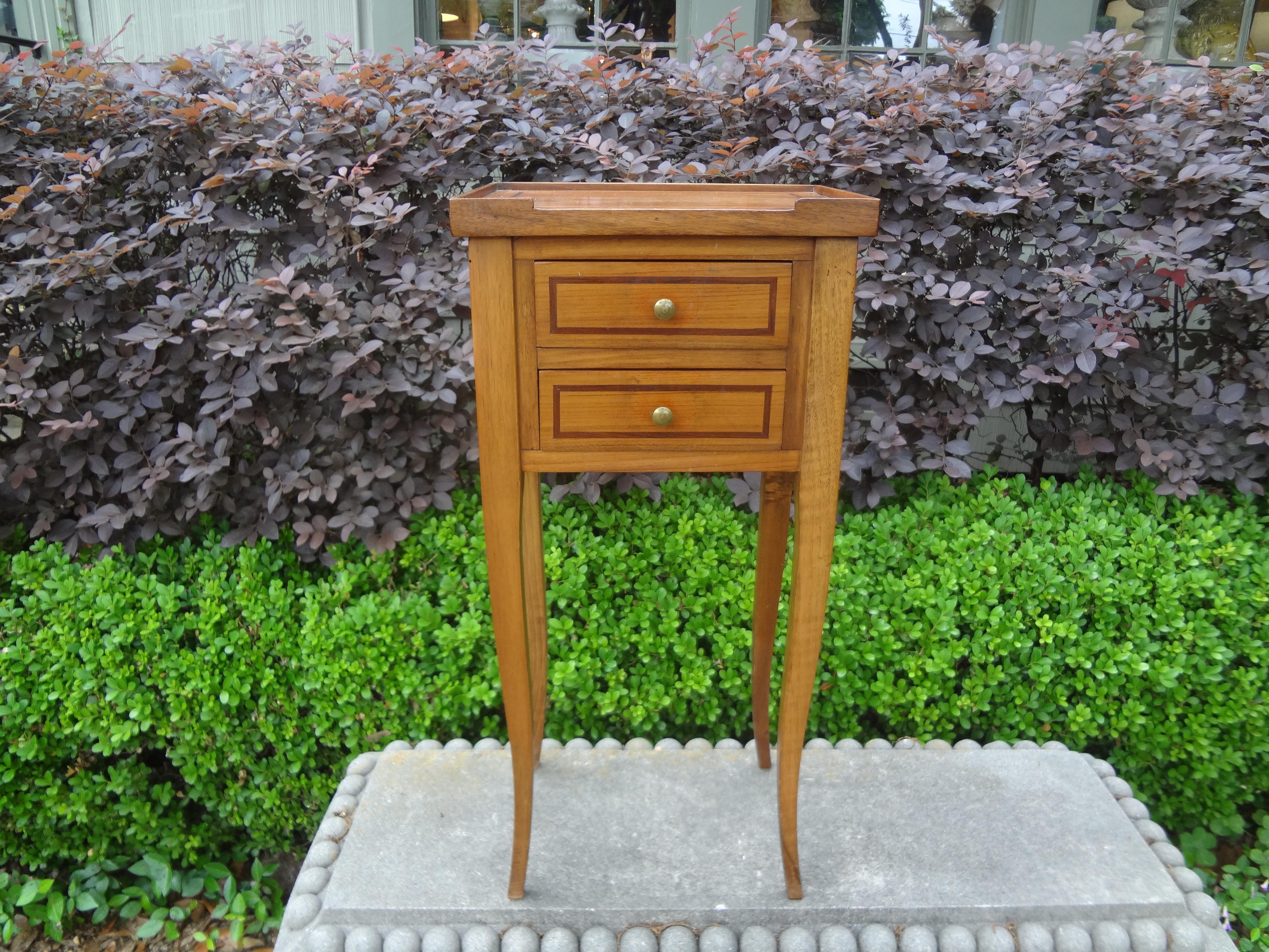 Stunning French Louis XVI style fruitwood side table or bedside table/nightstand. This charming French table has two drawers banded in a darker wood with bronze hardware and graceful legs.