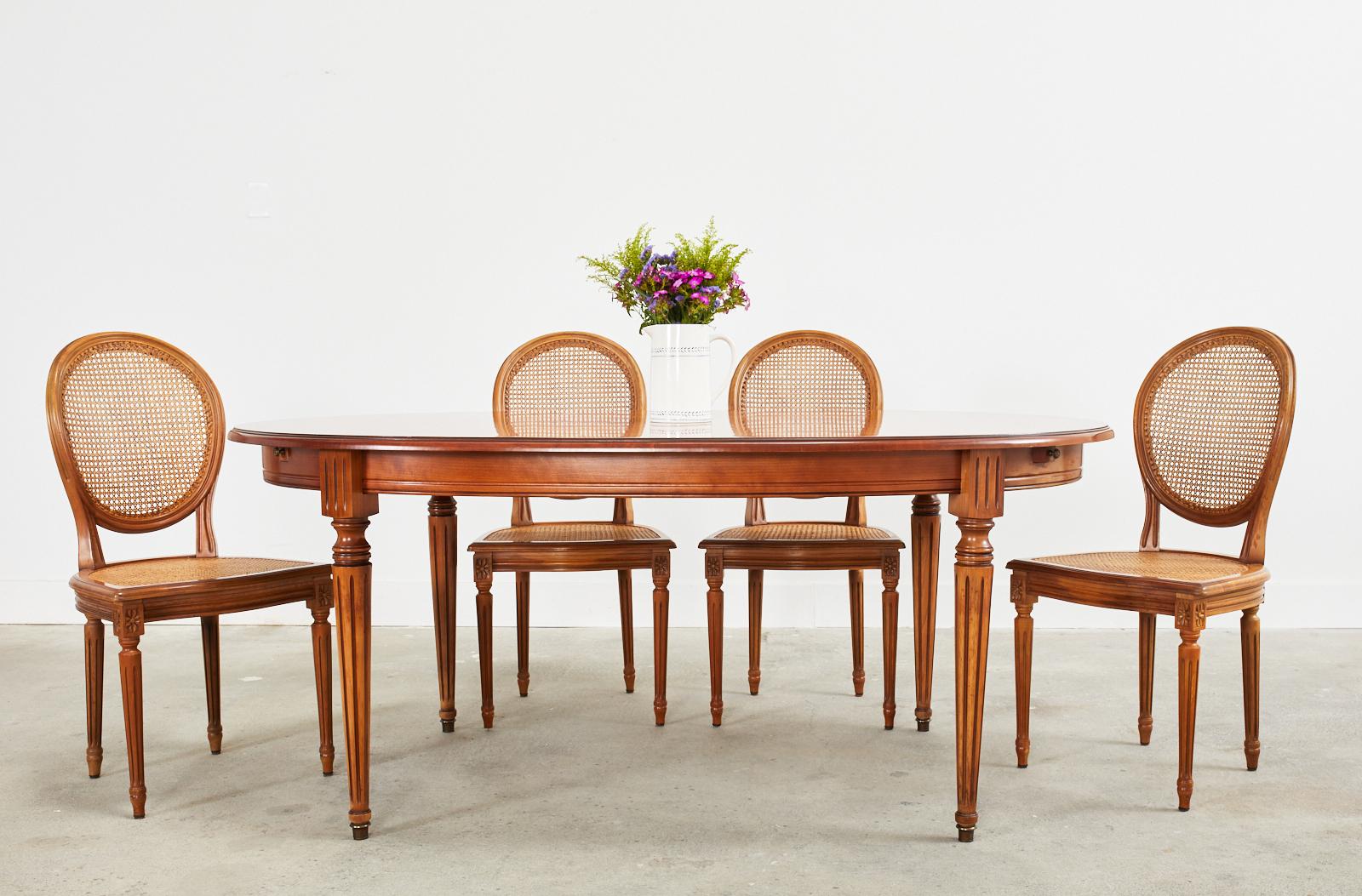 Handsome French dining table with two extending leaves made in the grand Louis XVI style. Constructed from fruitwood giving the table a warm honey tone that is not as formal as a dark mahogany version. The table has an oval form with pull out