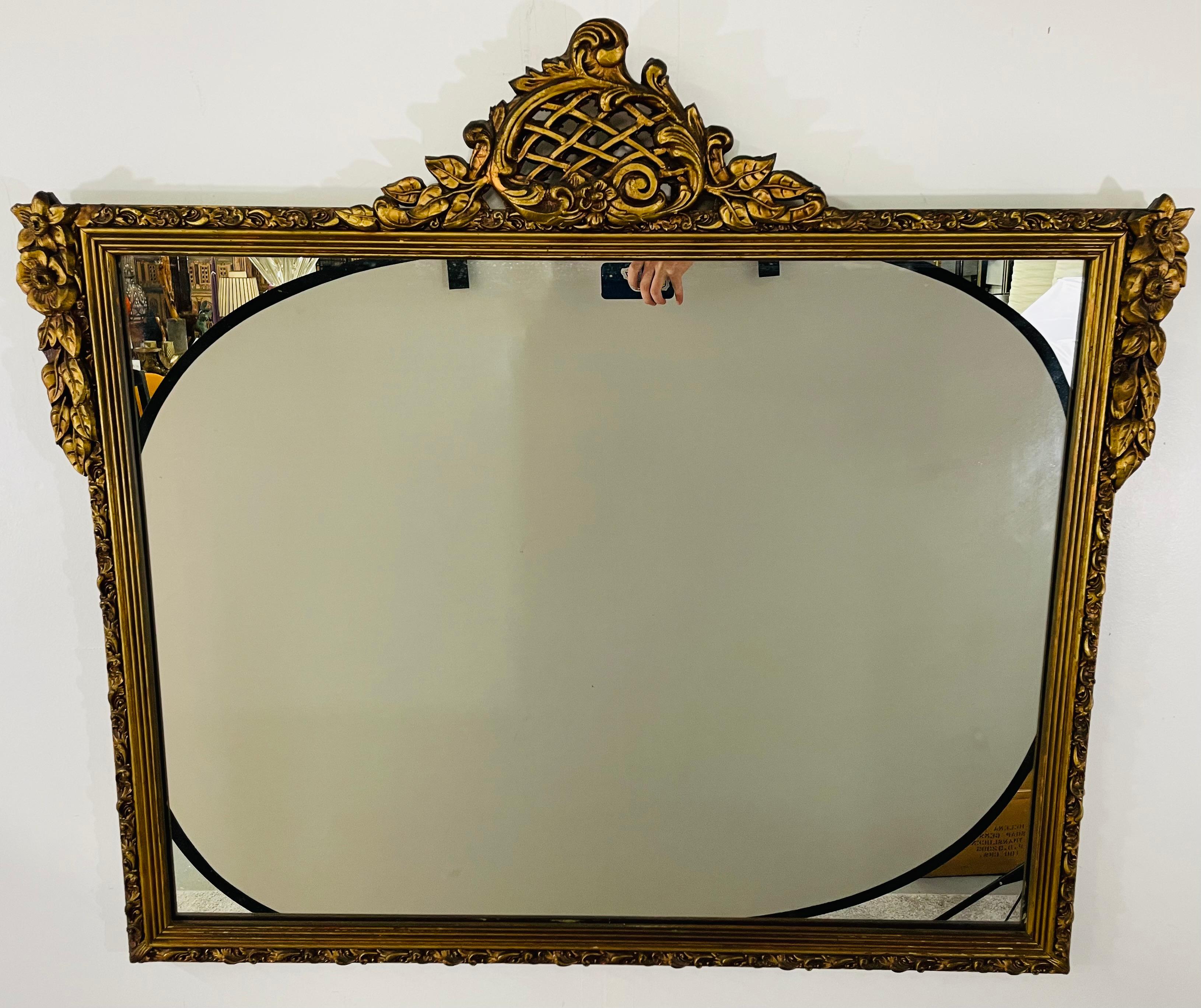 An exquisite 19th century French Louis XVI gilded mirror. The rectangular mirror is embellished with a magnificent crown featuring scrolls and leaves. The frame is finely hand carved and decorate with floral motifs on each top corners. The entire