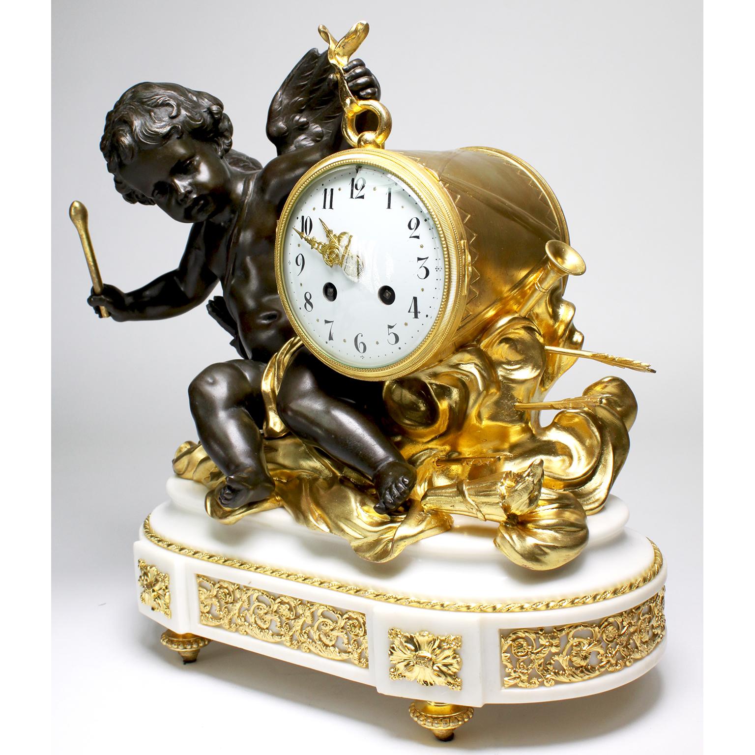 A fine French Louis XVI Style gilt and patinated bronze and white marble figural mantel clock with a figure of a drummer cherub. The brown patina cupid, seated on gilt-bronze clouds with arrows, flutes and a flaming torch, holding the drum-clock and