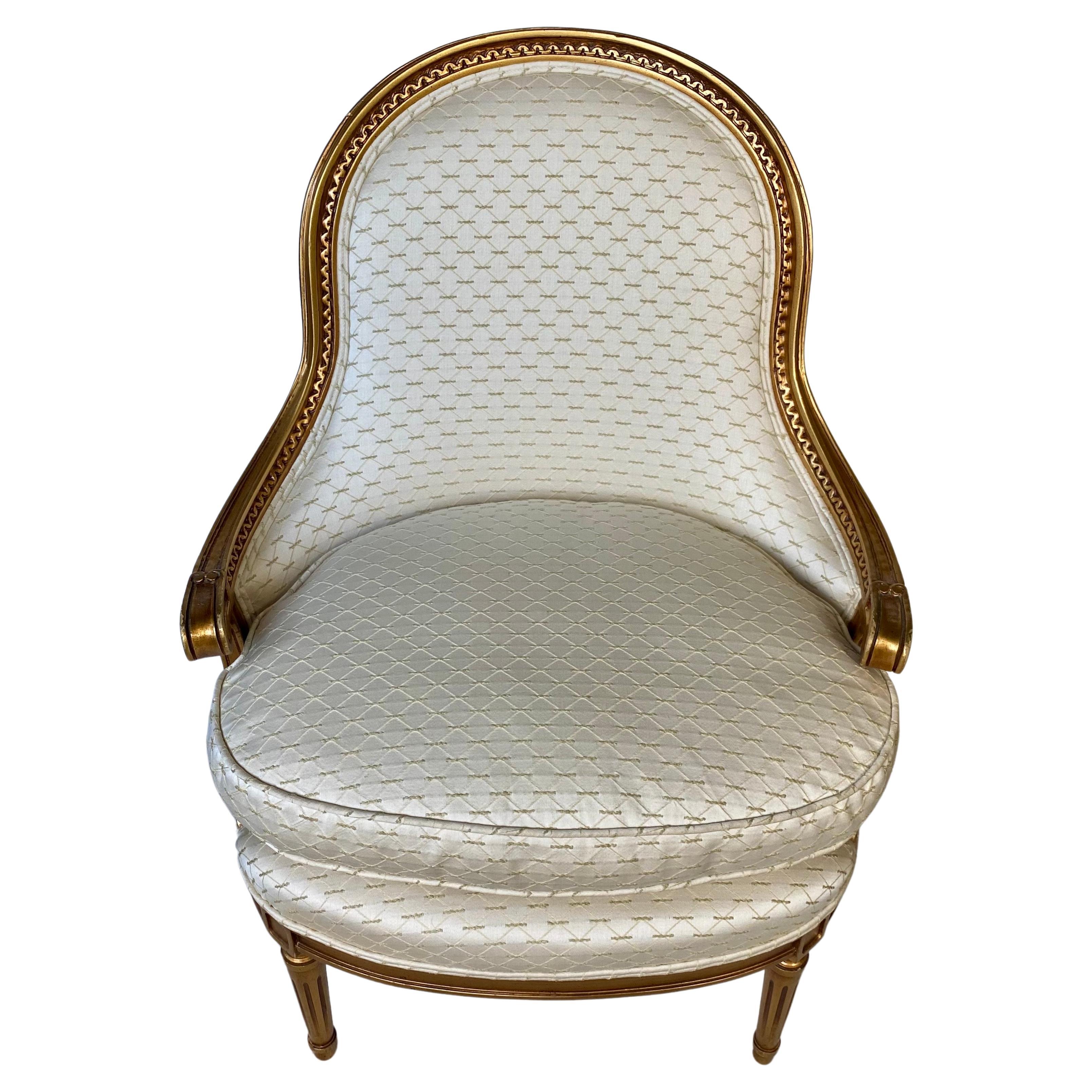 Louis XVI style giltwood barrel back bergère armchair, early 20th Century. This classic Neoclassical tub chair features a curved beautifully carved giltwood frame raised on tapered fluted legs. Removable seat cushion is filled with plush goose down.