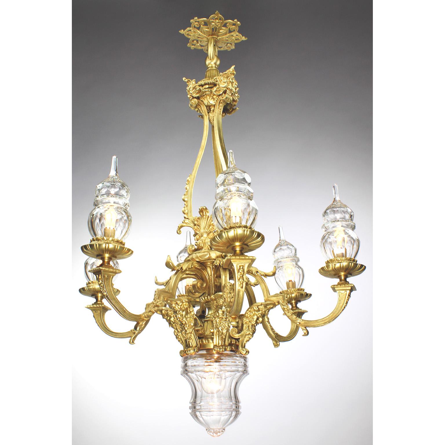A French Louis XVI style gilt-bronze and blown cut-glass seven-light figural chandelier in the manner of Baccarat. The elongated gilt-bronze body surmounted with acanthus and leaf decorations, with six scrolled candle-arms, each fitted with domed