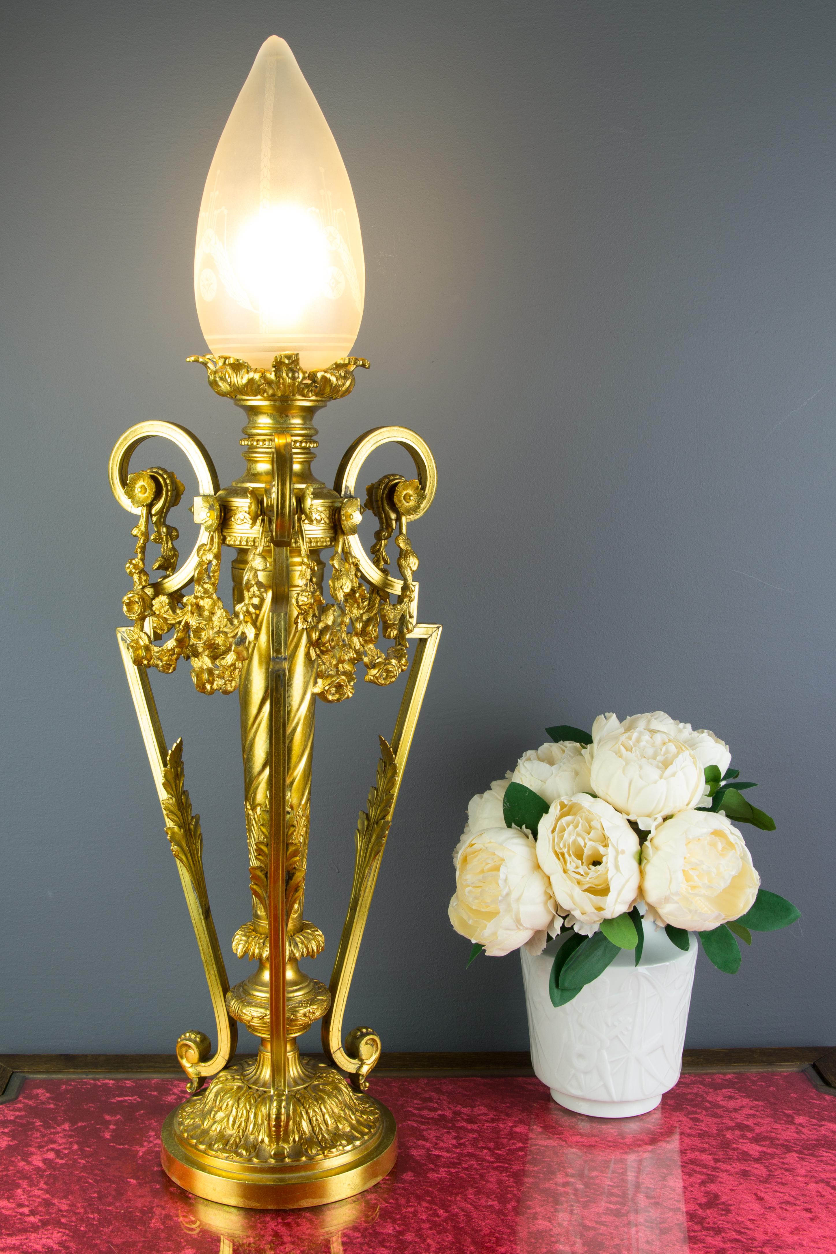 French Louis XVI style gilt bronze newel post lamp with frosted glass flame shade and an E27 socket, France, 1920s.
Richly decorated with bronze decors in a form of acanthus leaves and floral garland drapes.
Generally, in very good condition, it