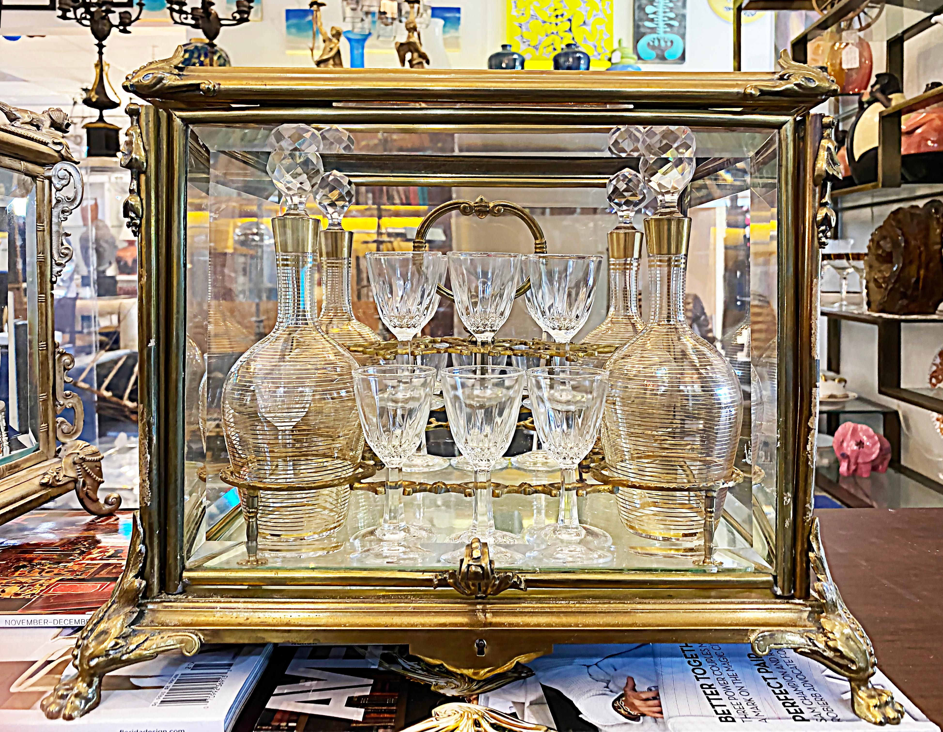 French Louis XVI Style Gilt Bronze Tantalus and Glassware Set, Late 19th Century

Offered for sale is a French Louis XVI style gilt bronze tantalus and glassware set dating from the late 19th century. This wonderful, decorative barware set has a