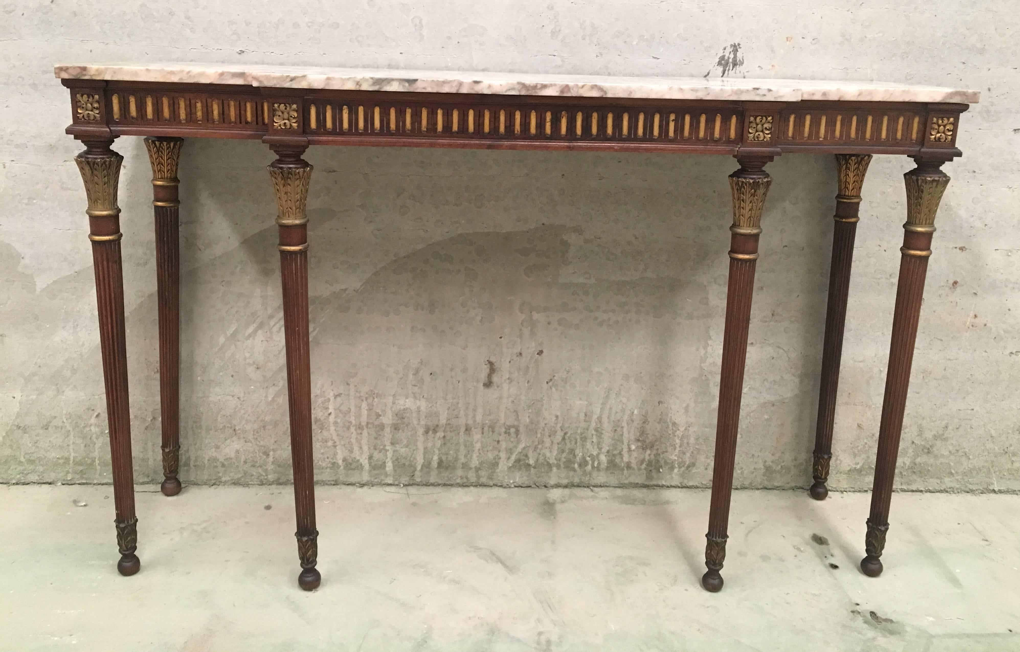 A French Louis XVI style marble and gilt painted wood console table from the mid 20th century. This French console table circa 1960 features a rectangular grey and white veined marble top over an exquisite painted body. The apron is carved with
